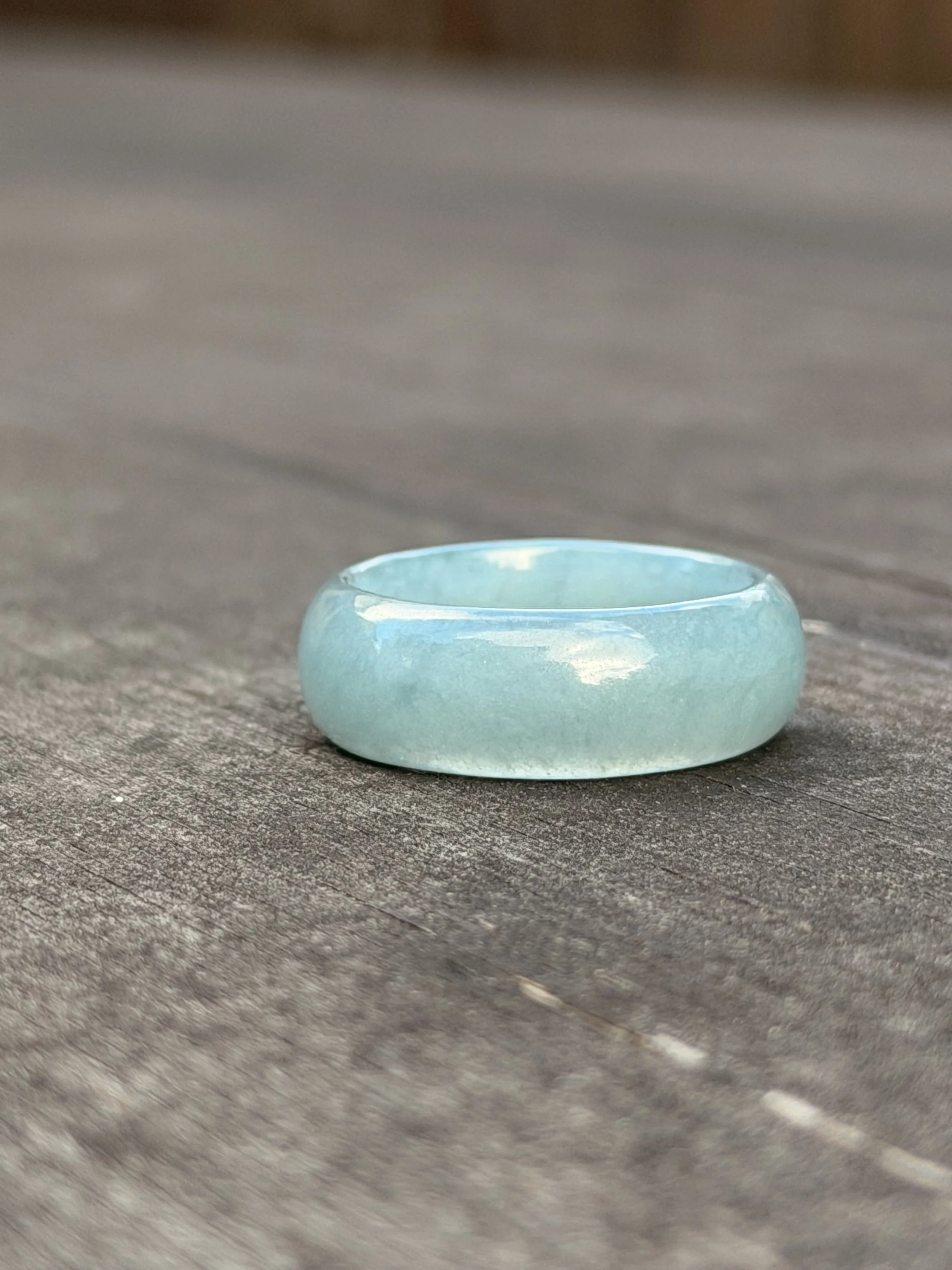 A light blue jadeite jade ring placed on a wooden surface.