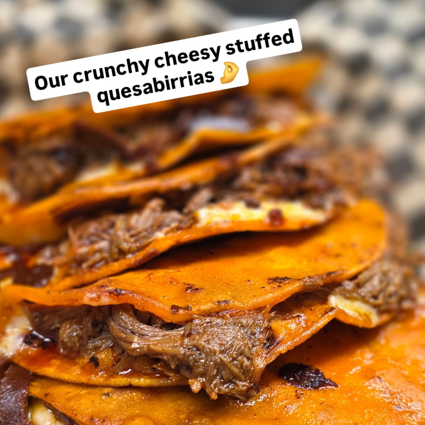 Close-up of stacked cheesy stuffed quesabirrias with shredded beef and melted cheese inside corn tortillas.
