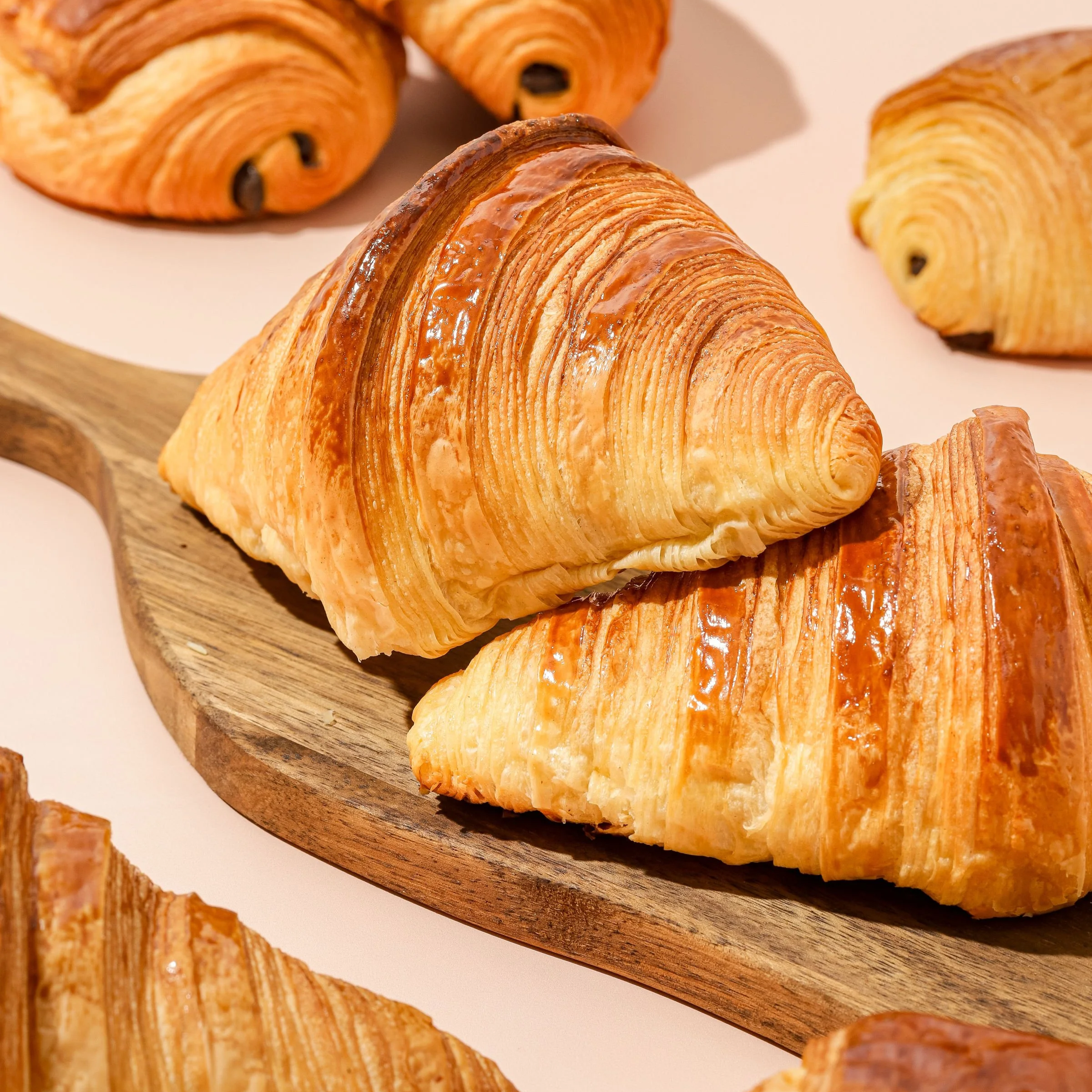 Croissants dorés et feuilletés disposés sur une planche en bois.