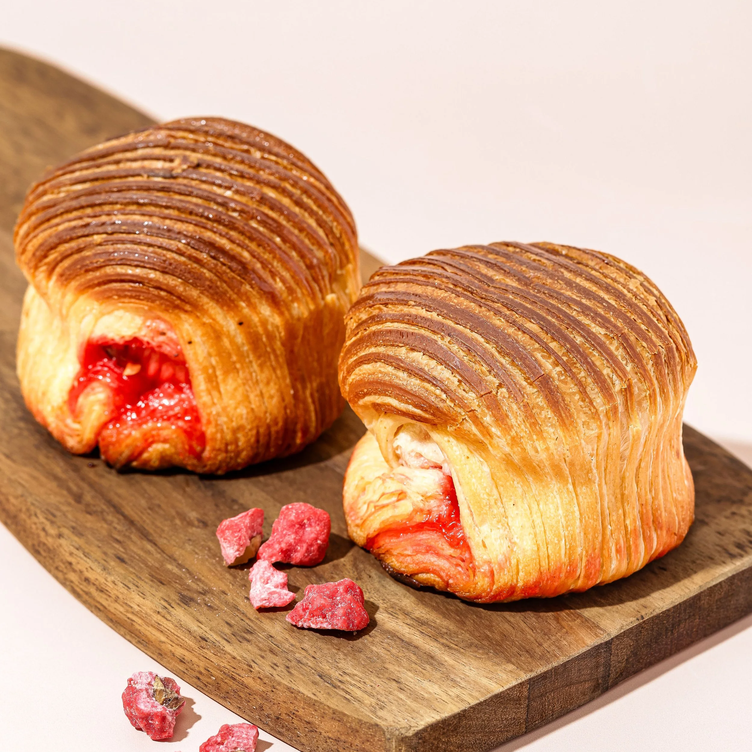 Deux croissants aux fruits rouges sur une planche en bois.