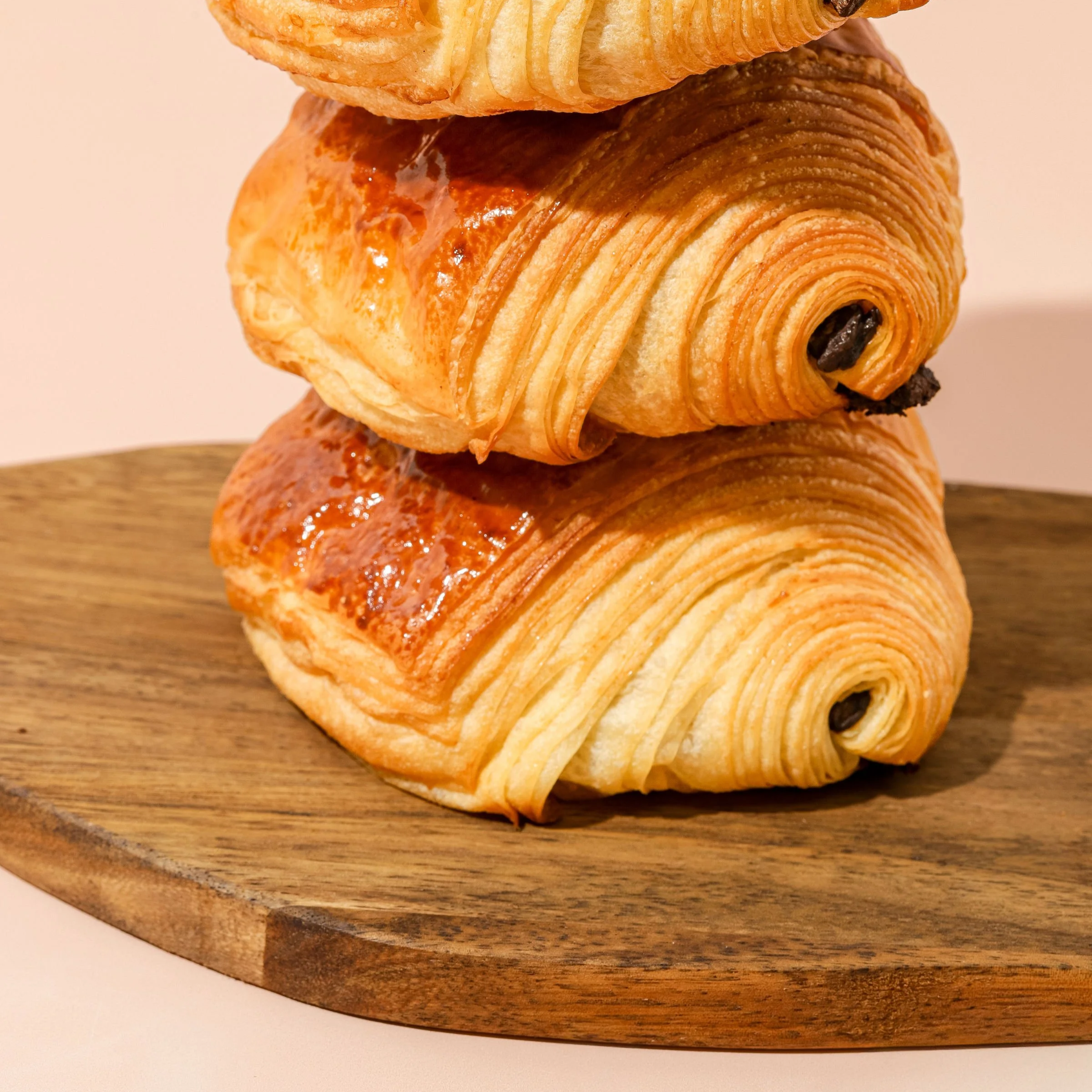 Trois croissants en pâtisserie sur une planche en bois.