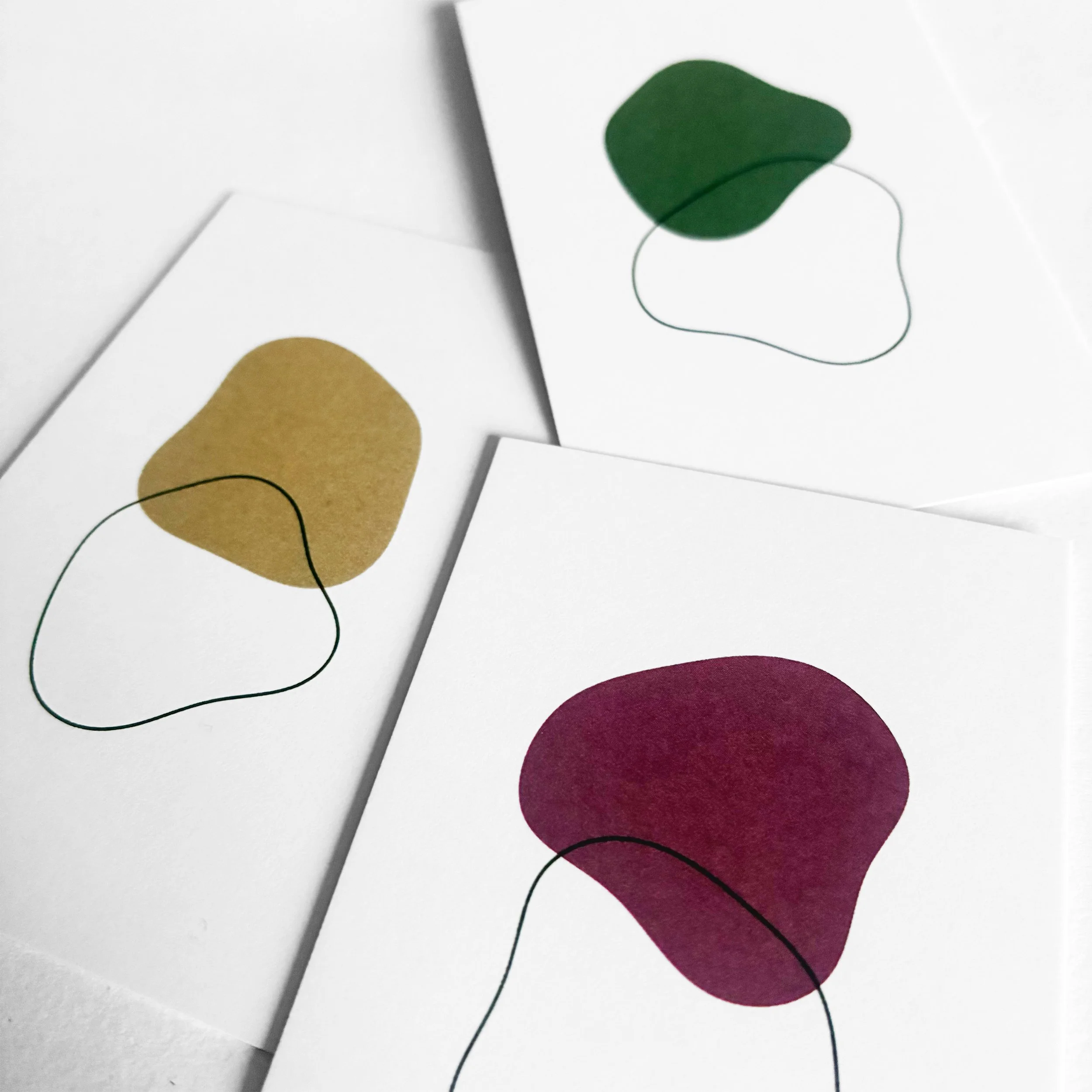 Dessins abstraits de formes ovales en couleurs verte, mauve, jaune sur fond blanc avec des lignes noires arquées.