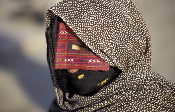 Person wearing a large patterned scarf covering most of their face and head, with only their eyes visible.