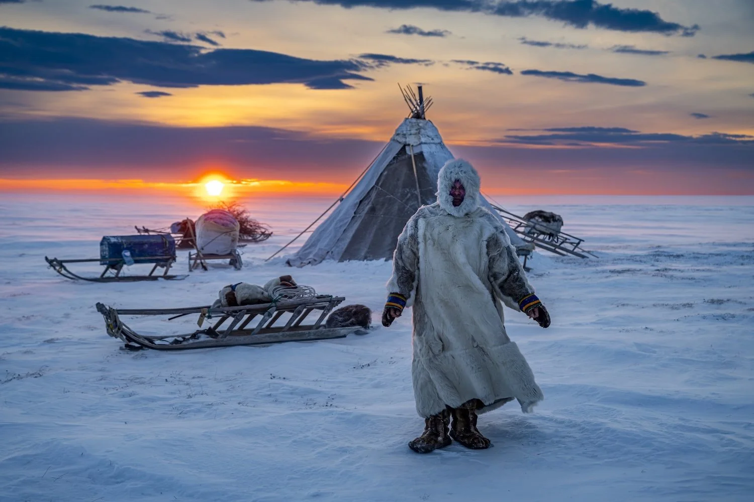 Nenet man in front of a traditional Chum at sunset, Yamal Peninsula, Russia.