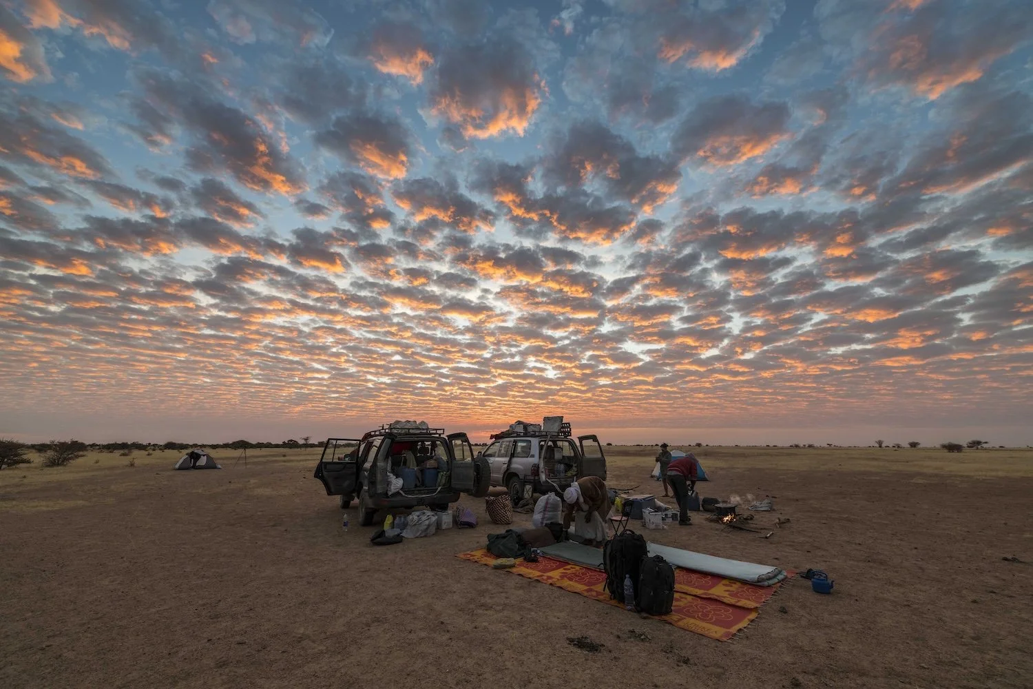 Camping under a dramatic morning sky in the Sahel Desert, Chad, Africa.