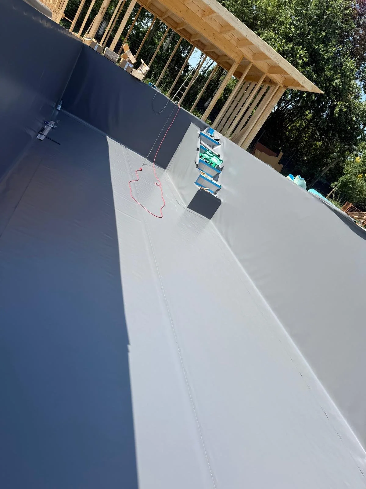 Bau eines Swimmingpools mit Holzrahmen im Außenbereich, mit diversen Baumaterialien und Werkzeugen.