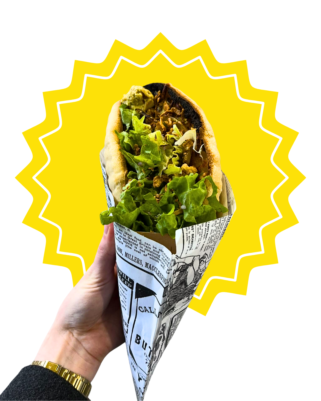 Une faluche remplie de salade verte, de viande, de concombre, et de sauce, enveloppé dans un papier avec des impressions de texte noir et blanc, tenue par une main