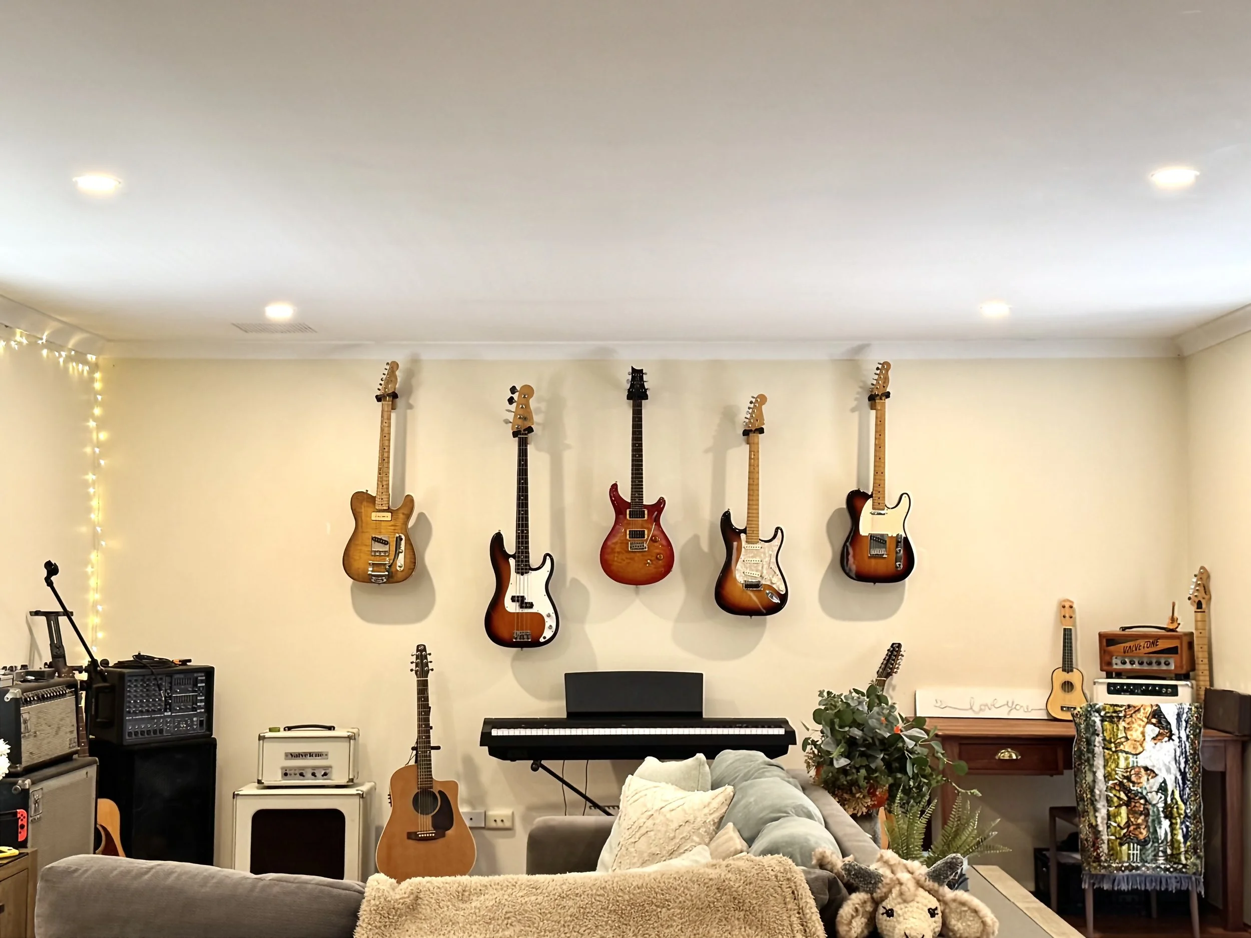 Living room with musical instruments, including guitars, a keyboard, and audio equipment, mounted on the wall and arranged around the room.