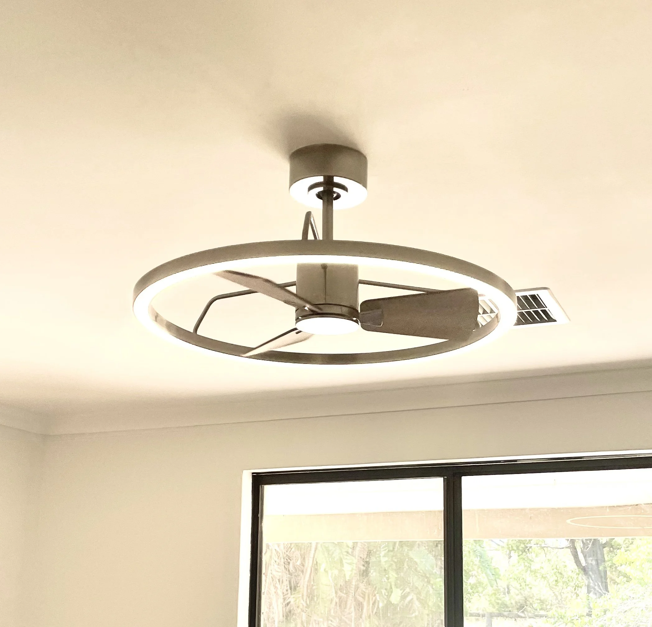 Modern ceiling fan with built-in LED light in a room with a window and natural light.