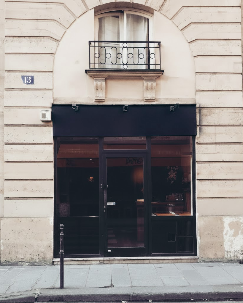 Façade d'un bâtiment avec une fenêtre à balcon au premier étage et une porte d'entrée vitrée au rez-de-chaussée.