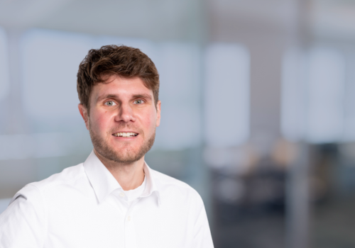 Jannik Schätzle, Key Account Manager mit weißem Hemd vor einem modernen Bürohintergrund.