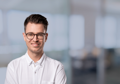 Christopher Siegel, Lead Web Developer bei den Digitalwandlern im weißen Hemd, lächelnd, im Büro.