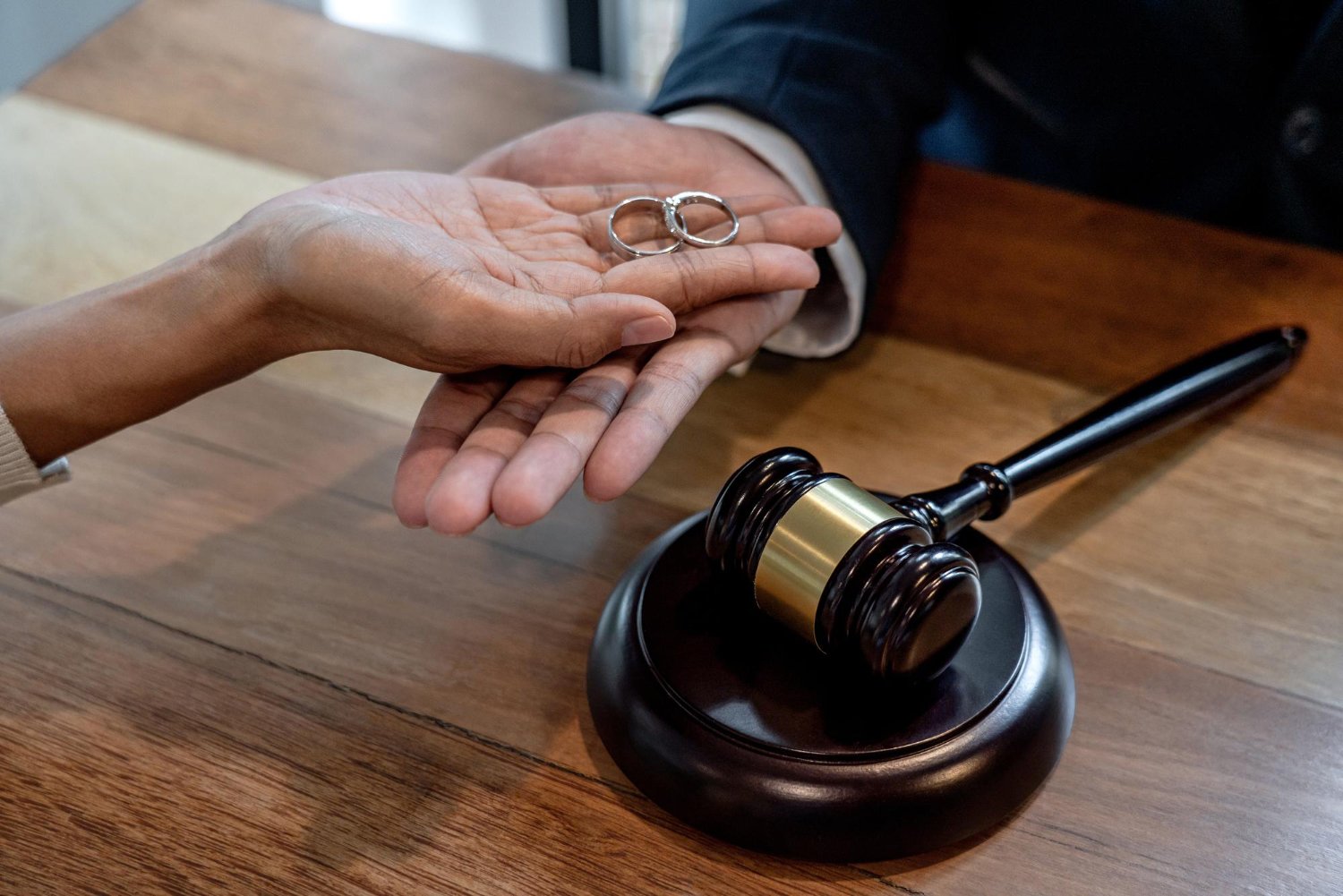 A person receiving a pair of wedding rings on a judge's bench in a legal or wedding ceremony setting with a gavel nearby.