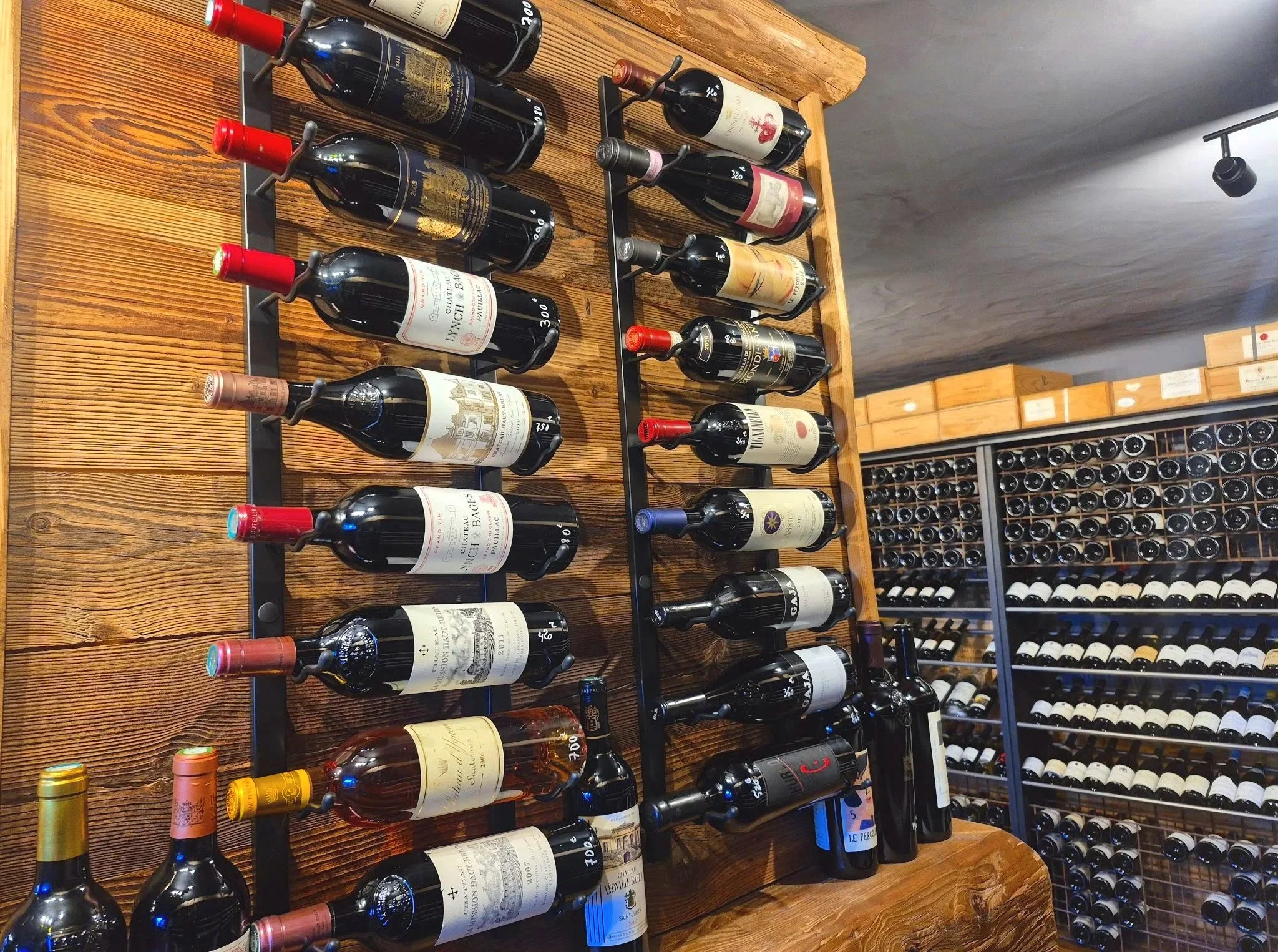 Étagère en bois avec des bouteilles de vin rouges et blancs exposées verticalement dans un magasin ou une cave à vin.