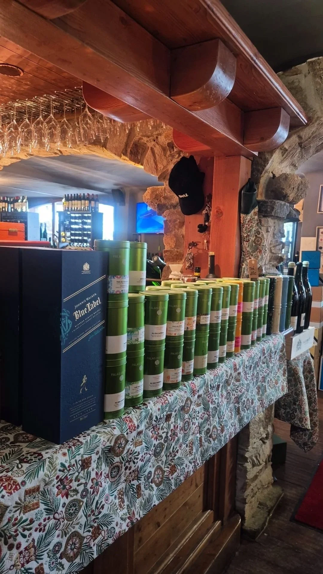 Étals avec des boîtes cylindriques vertes et des bouteilles noires dans un restaurant ou bar.