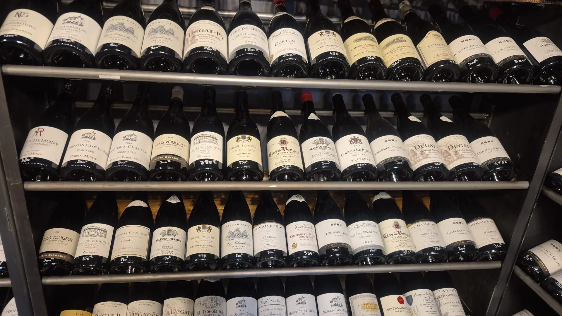 Étagère remplie de bouteilles de vin organisées par rangées.