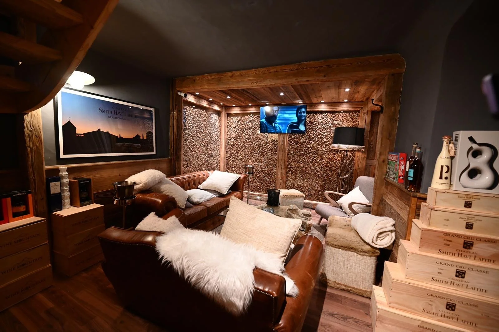 Salon de style cozy avec canapés en cuir marron, coussins, tapis en fourrure, murs en bois et une télévision