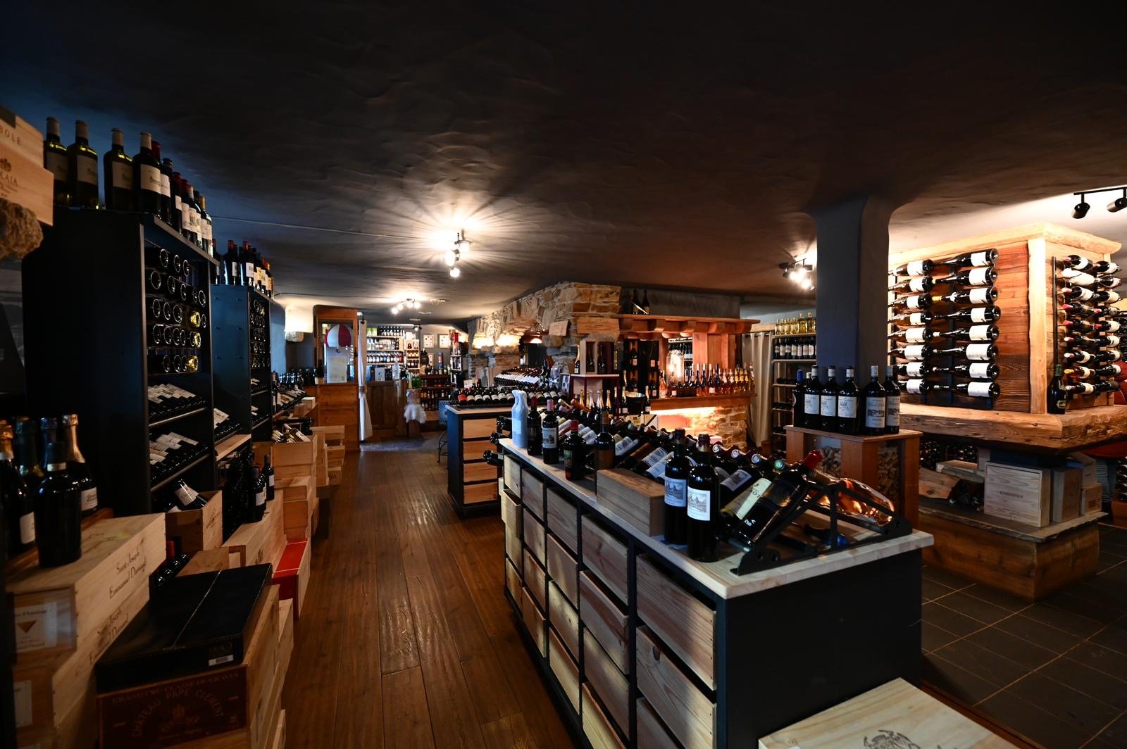 Intérieur d'une cave à vin chaleureuse avec étagères en bois remplies de bouteilles de vin, éclairage tamisé, plancher en bois et murs en pierre.