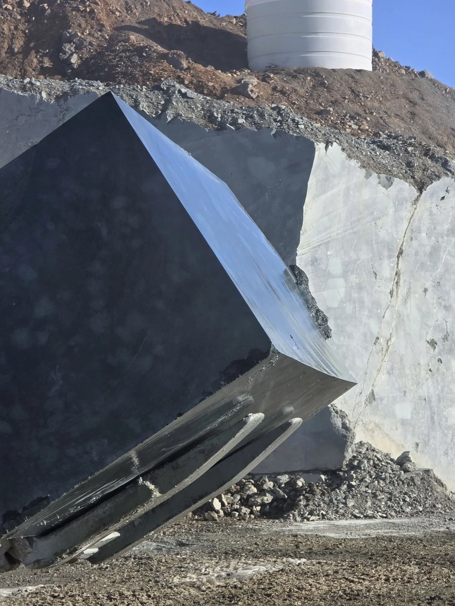 Close-up of large black and white marble slabs with a mountain landscape and a white cylindrical structure in the background.
