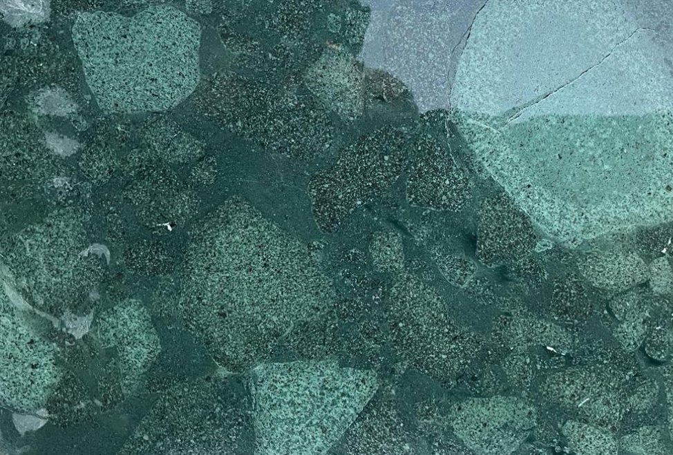 Close-up of a geometric mosaic pattern made of small green and gray stones.