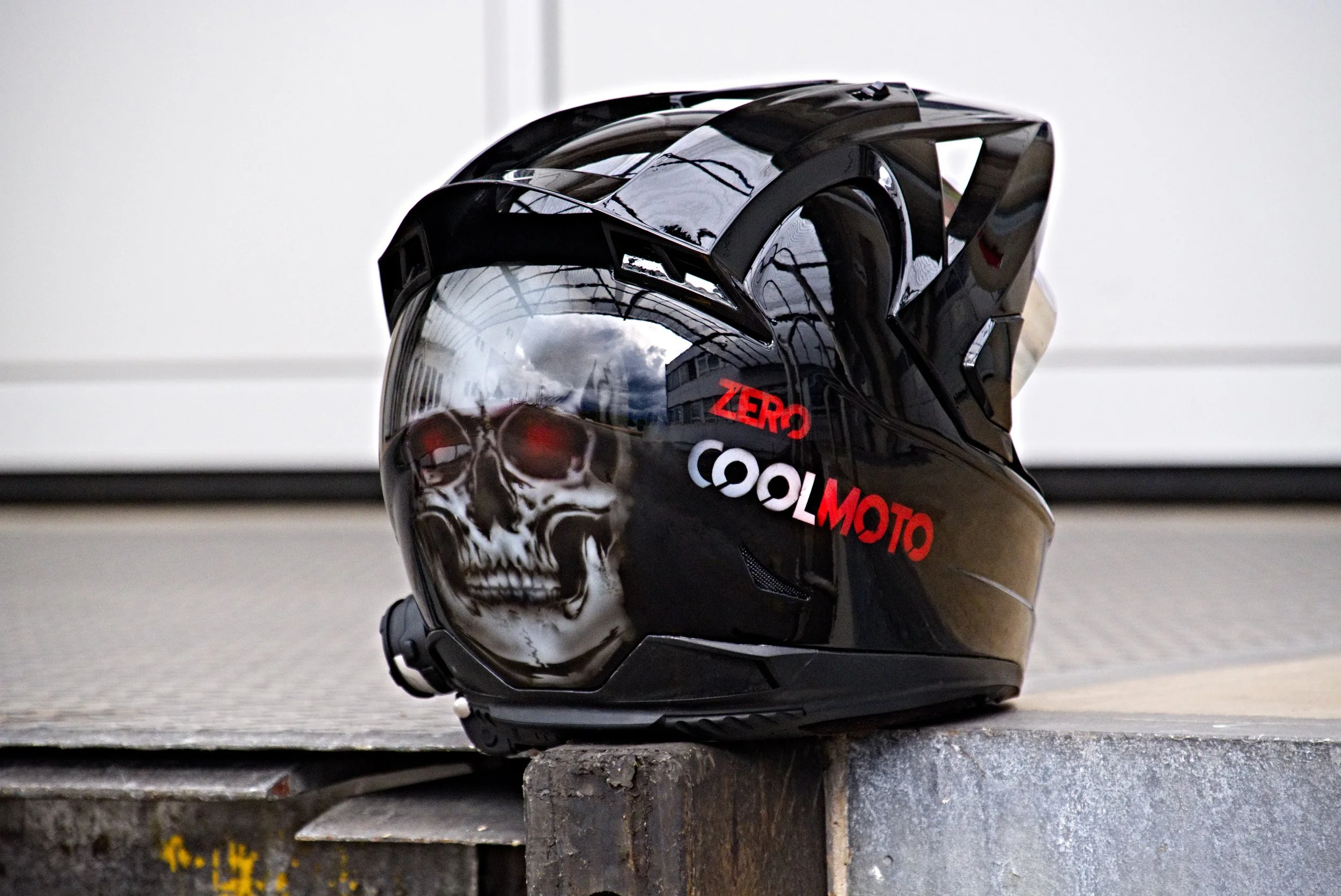 Motorradhelm mit Skull-Design und Text 'ZERO COOLMOTO' auf einer Treppenstufe.