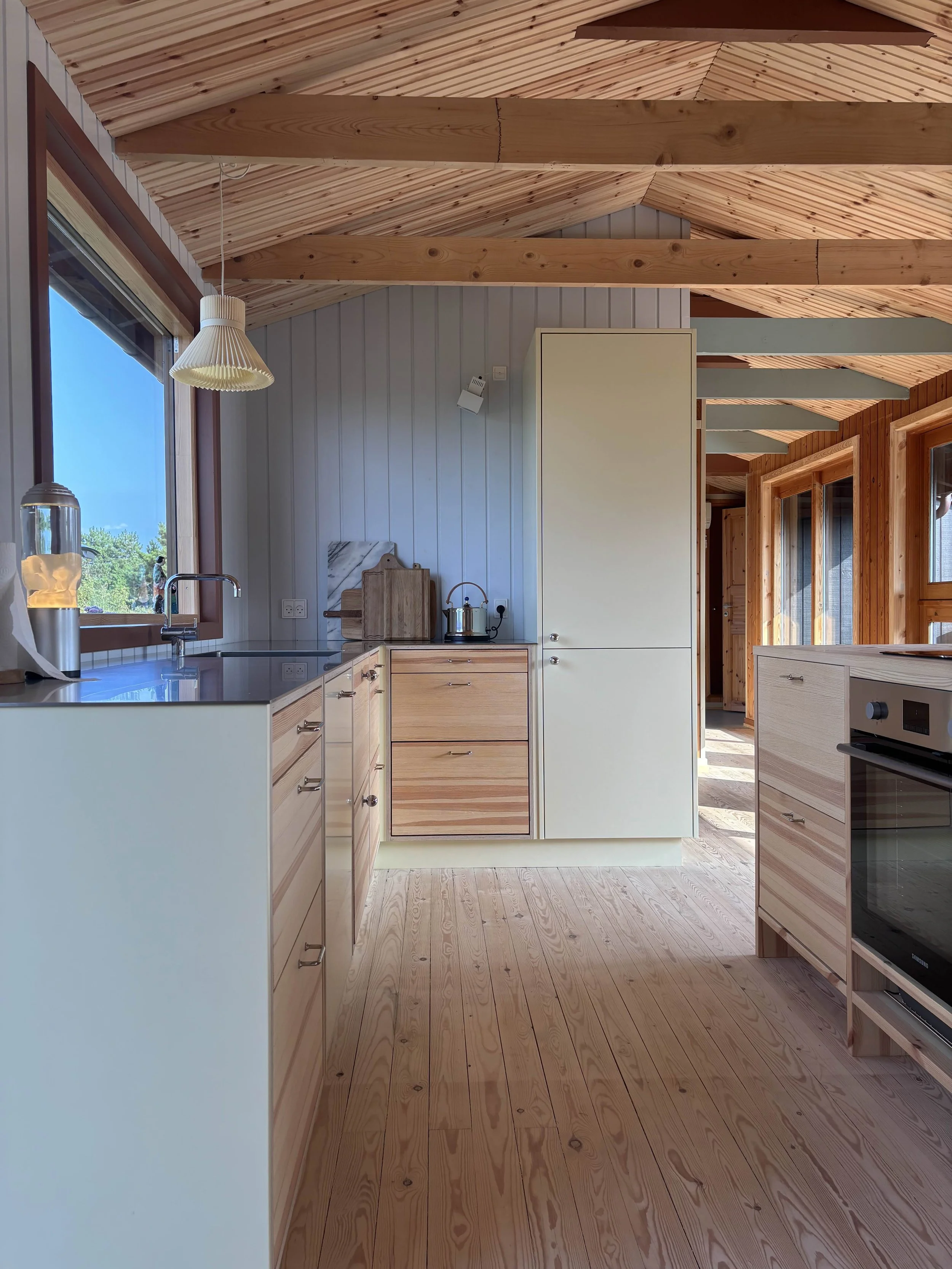 Køkken i olieret fyrretræ. Synlige skuffer og en sart sprøjtemalet lysegul.