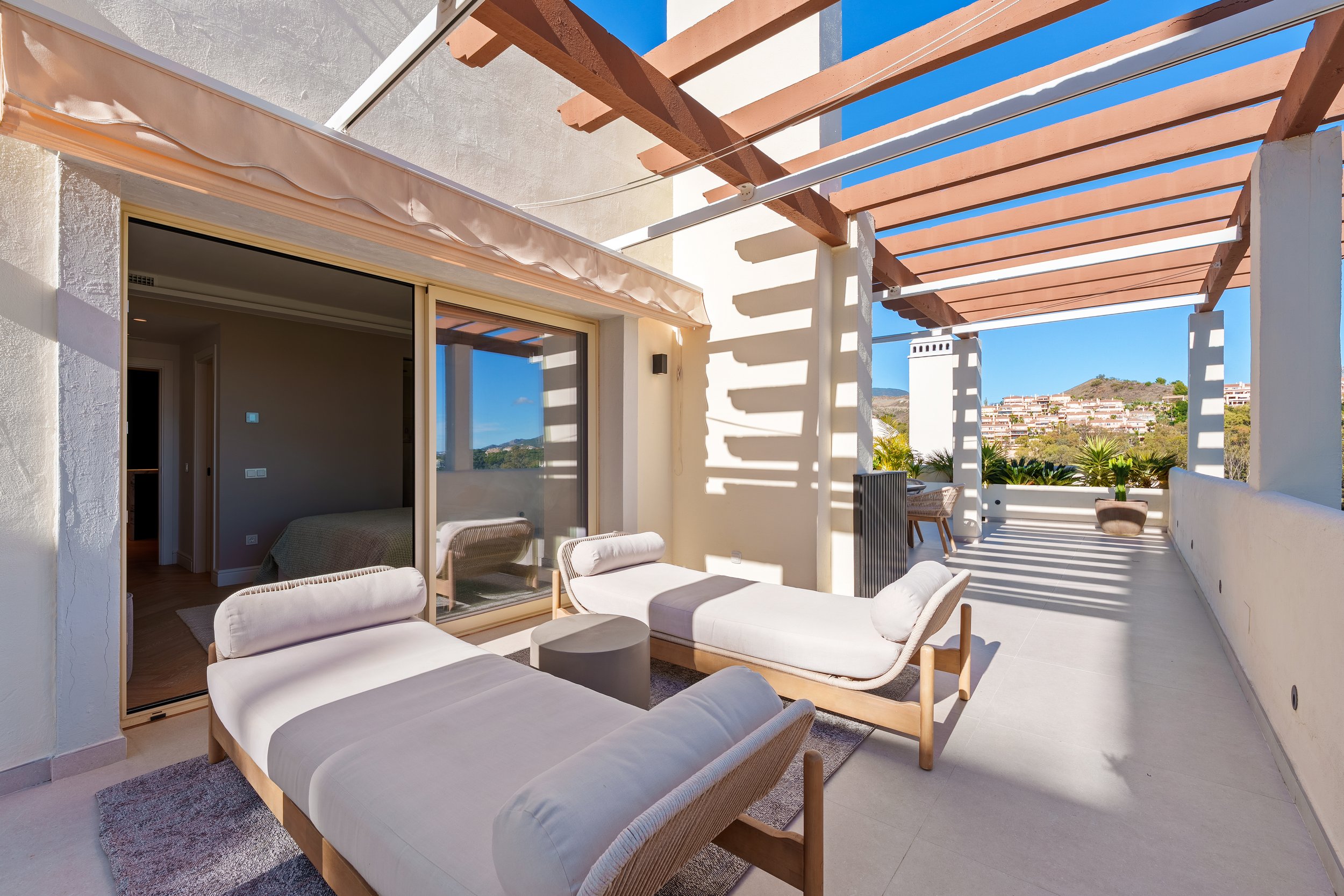 Sun-drenched terrace at sunset featuring luxury sun loungers and views of the sea, lake, and mountains
