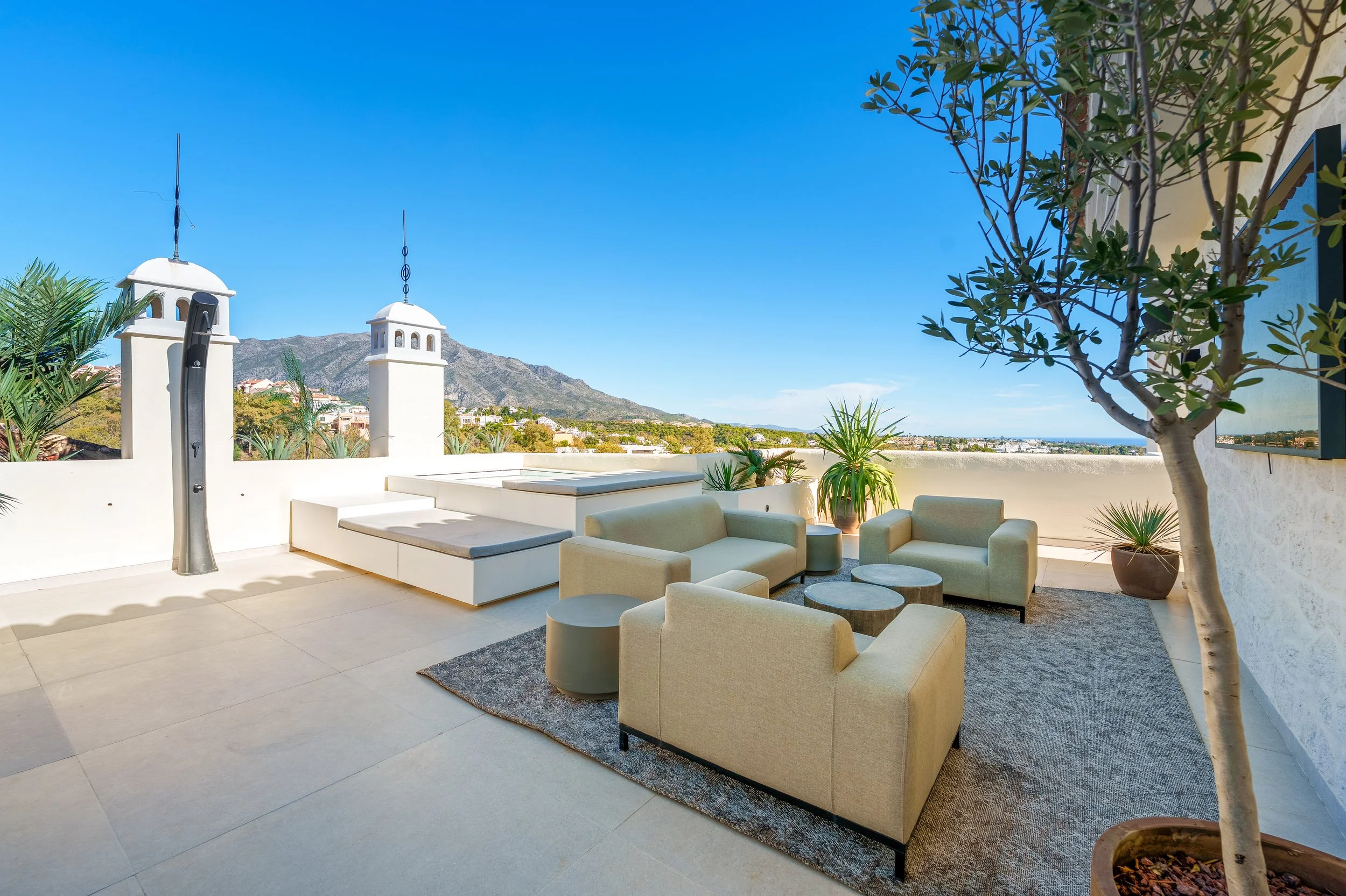 Spacious upper-level terrace featuring modern outdoor lounge seating, neutral-toned upholstery, and views of La Concha mountain.