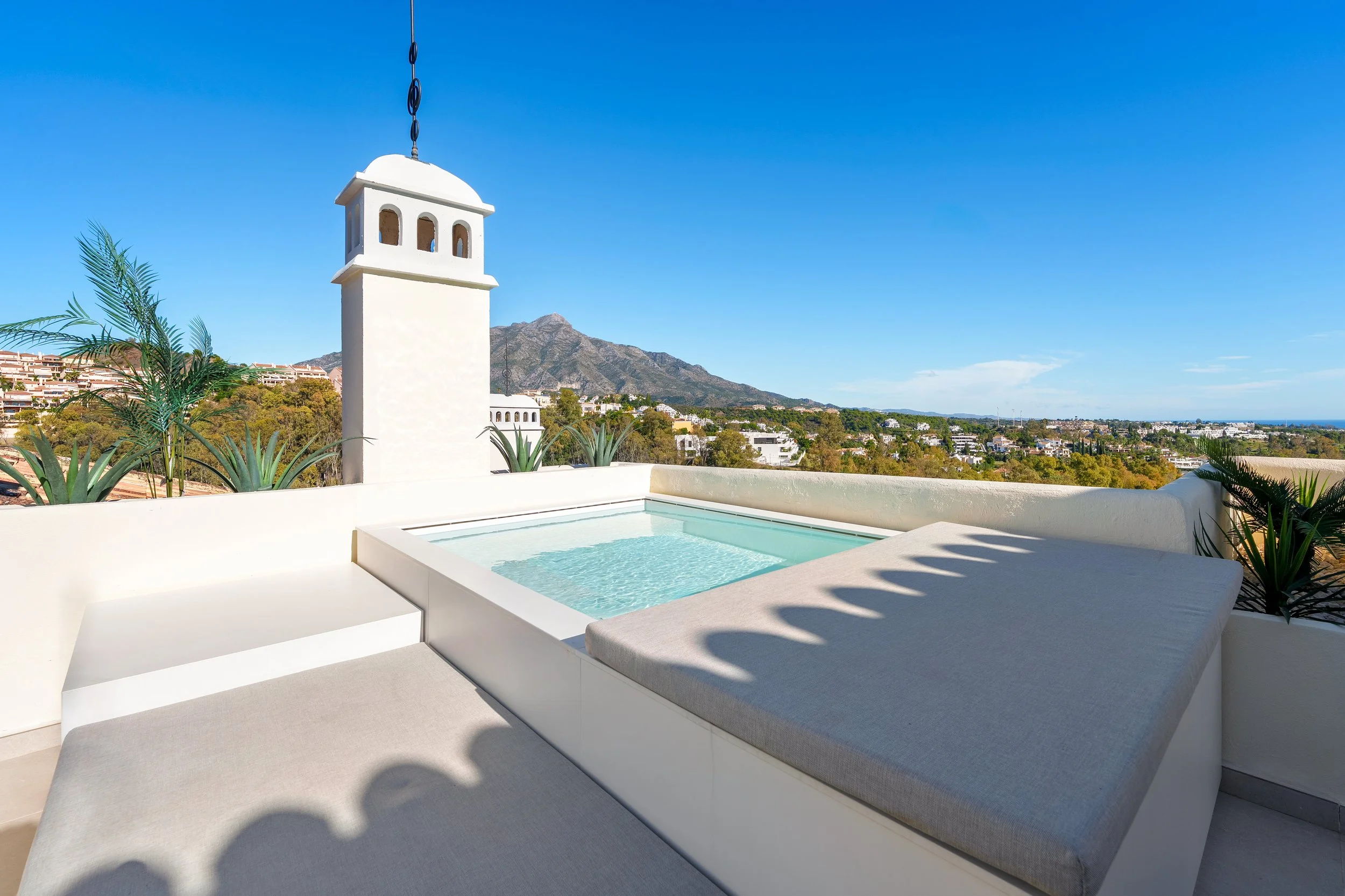 Modern rooftop plunge pool with integrated seating, surrounded by a clean minimalist deck and overlooking the Mediterranean coastline