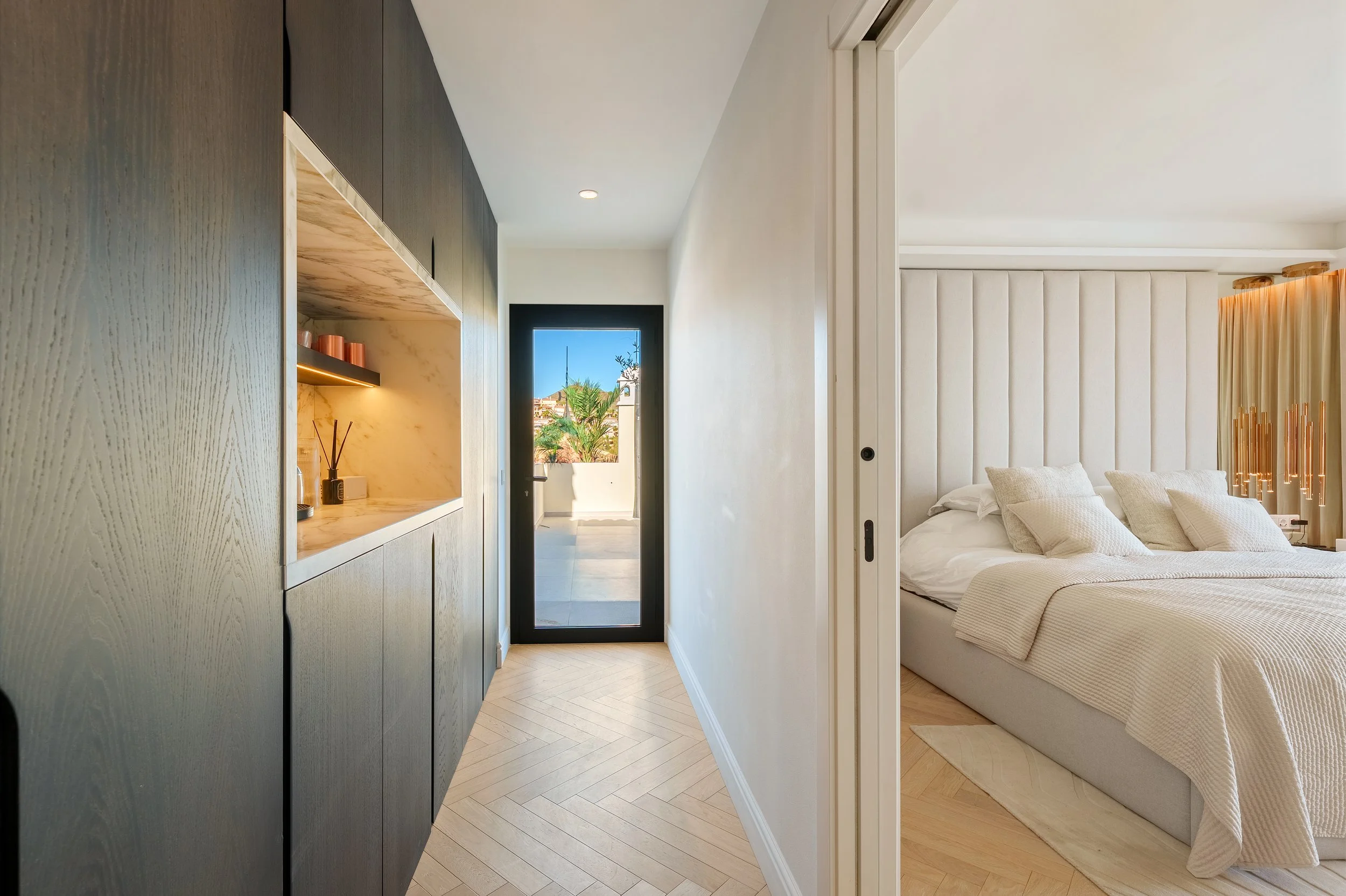 Minimalist hallway with seamless built-in storage and oak flooring, leading toward the bright bedroom suites.