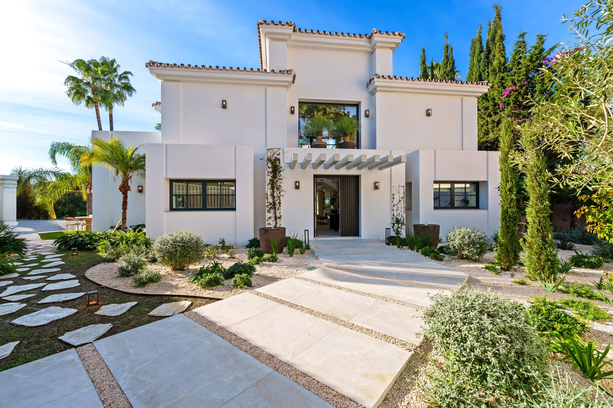 A minimalist, modern entryway with geometric stone tiling and manicured desert-style landscaping.