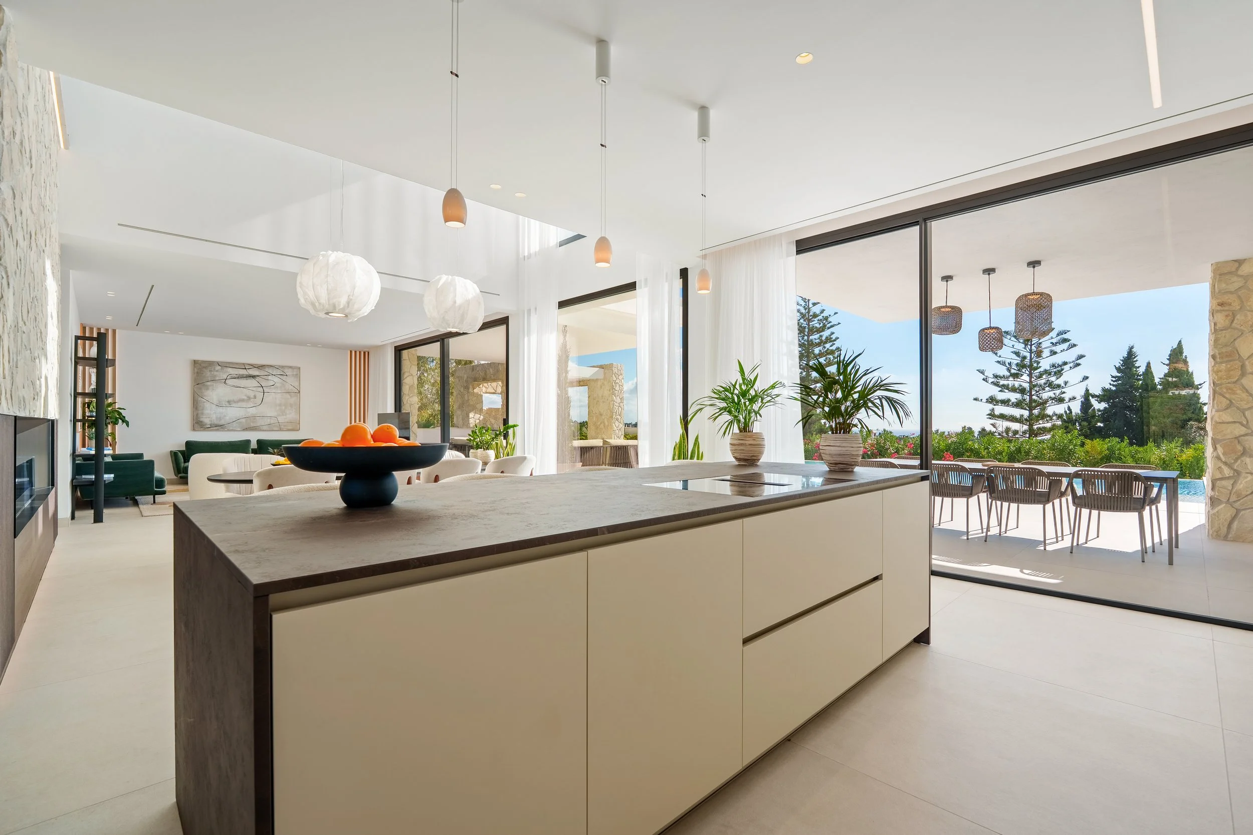 A minimalist chef’s kitchen with a large central island, integrated high-end appliances, and sleek handle-less cabinetry.