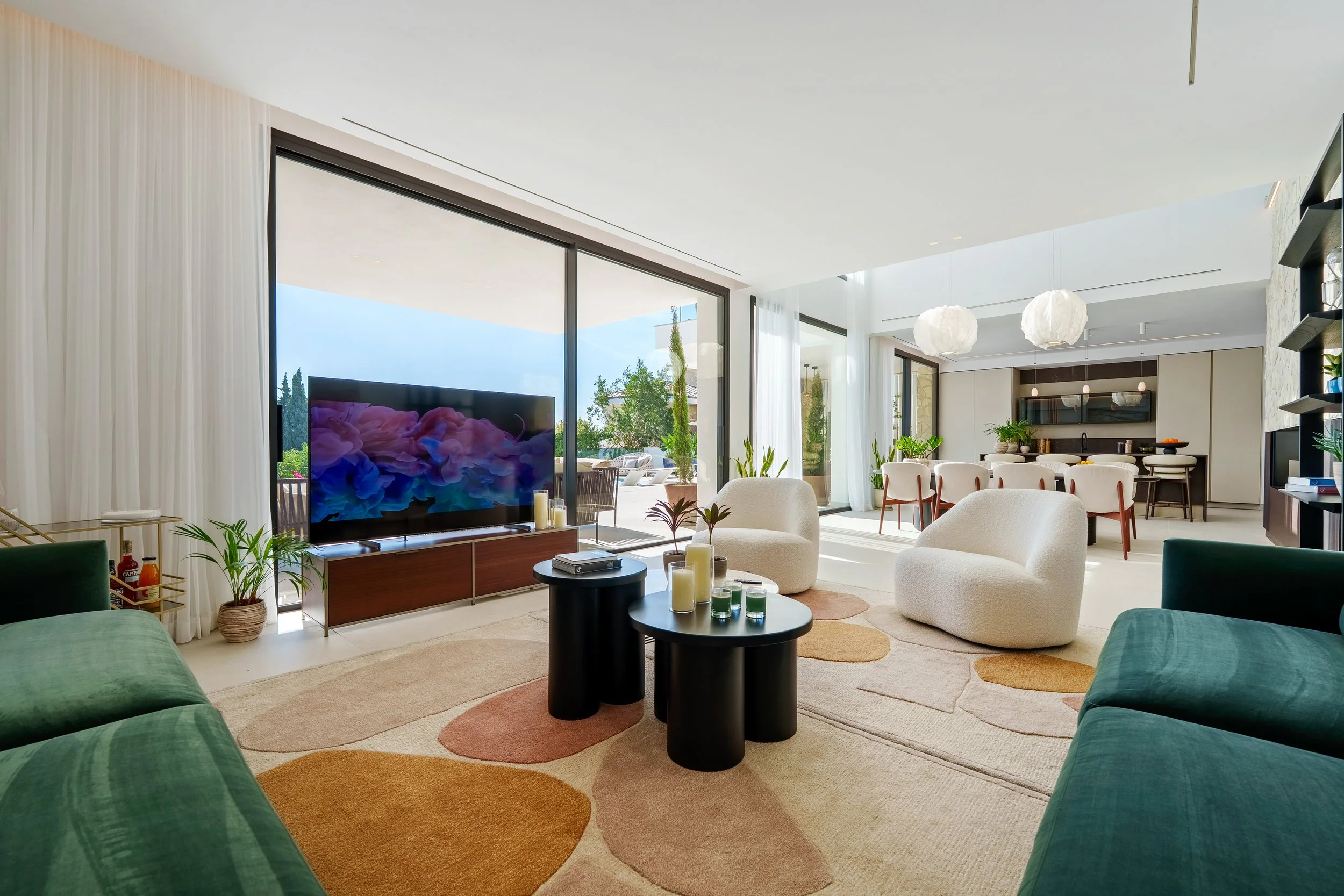A bright, double-height dining space featuring a modern oval table and designer pendant lighting, perfectly positioned for panoramic views.