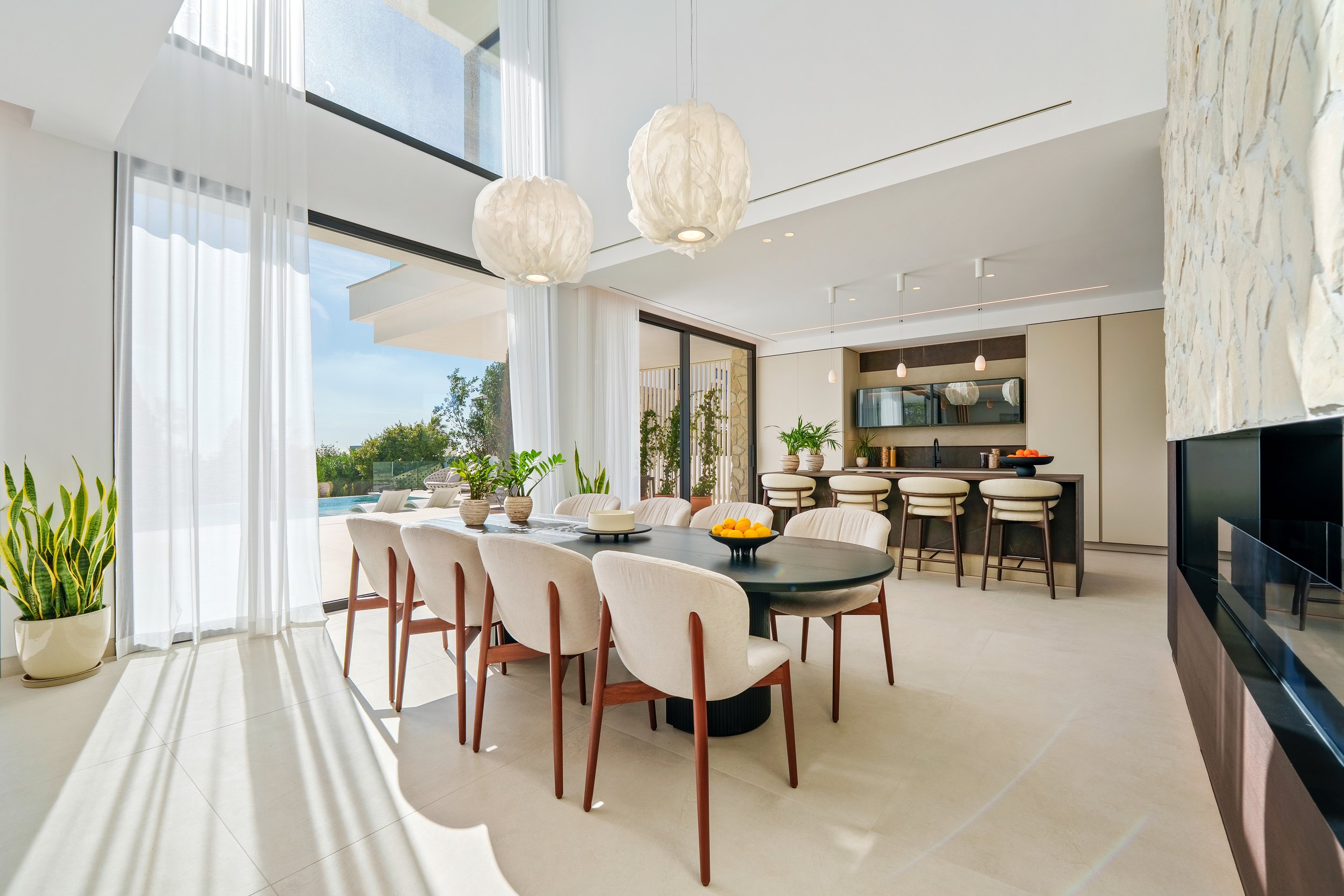 A sophisticated lounge area with plush green velvet seating, custom wood paneling, and direct access to the main terrace through sliding glass walls.