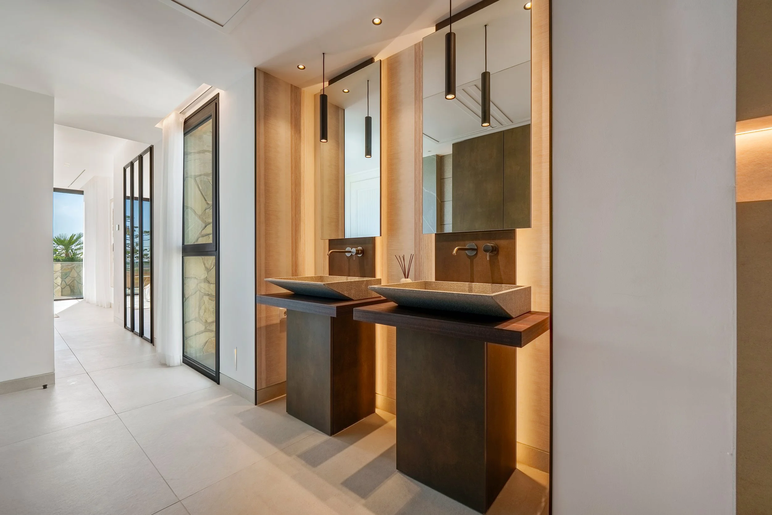 A spacious, walk-in master wardrobe with floor-to-ceiling smoked glass doors and integrated LED lighting