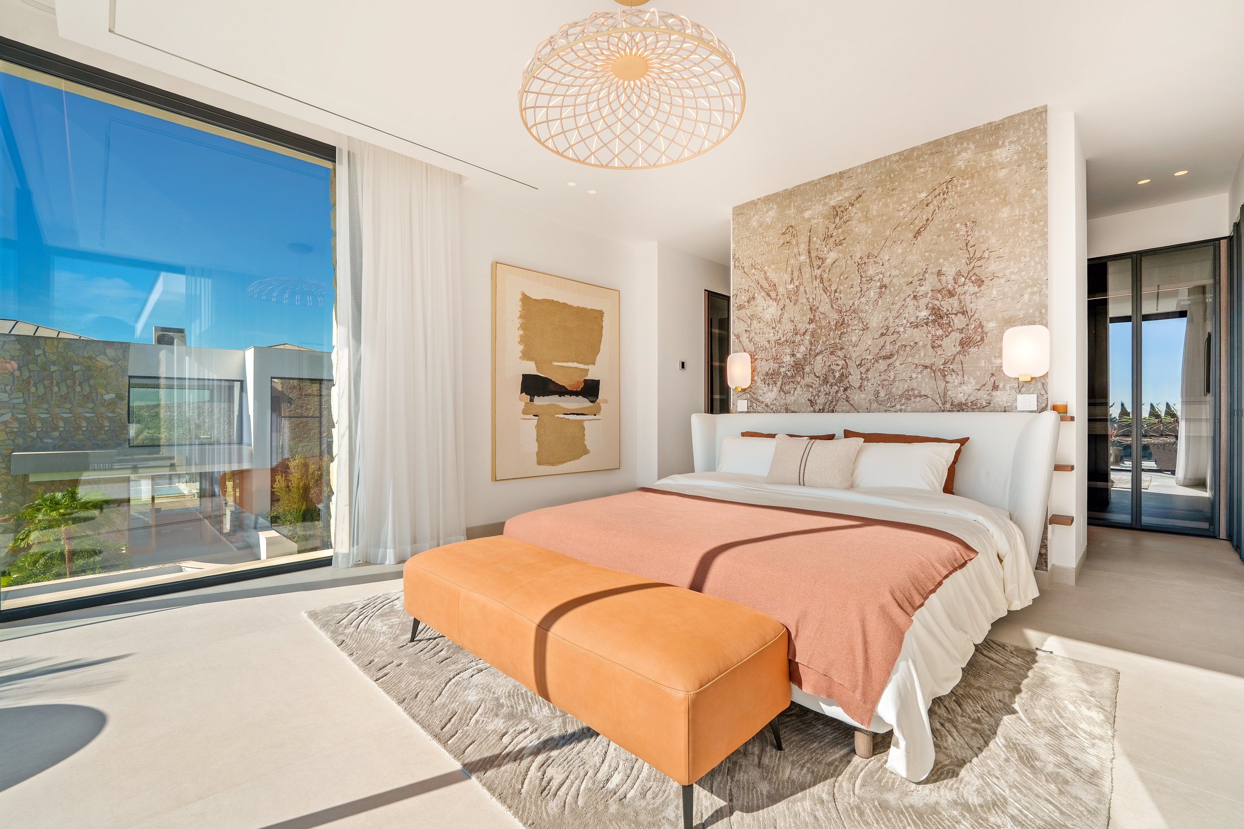 A luxurious retreat on the upper level featuring a private terrace, custom headboard wall, and breathtaking views of the Mediterranean coast