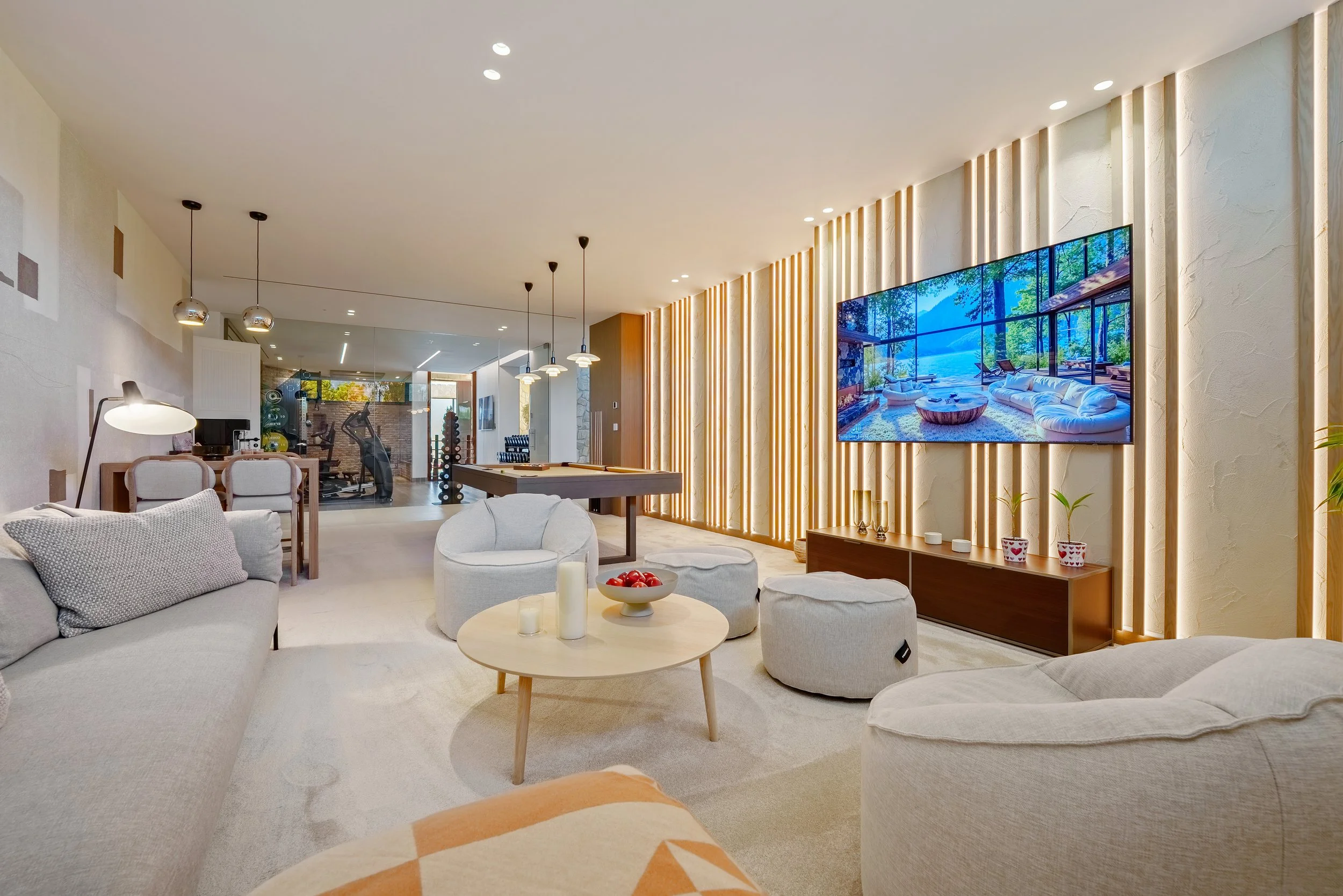 A versatile lower-level space featuring a cinema area, games table, and custom wood-slat wall treatments.