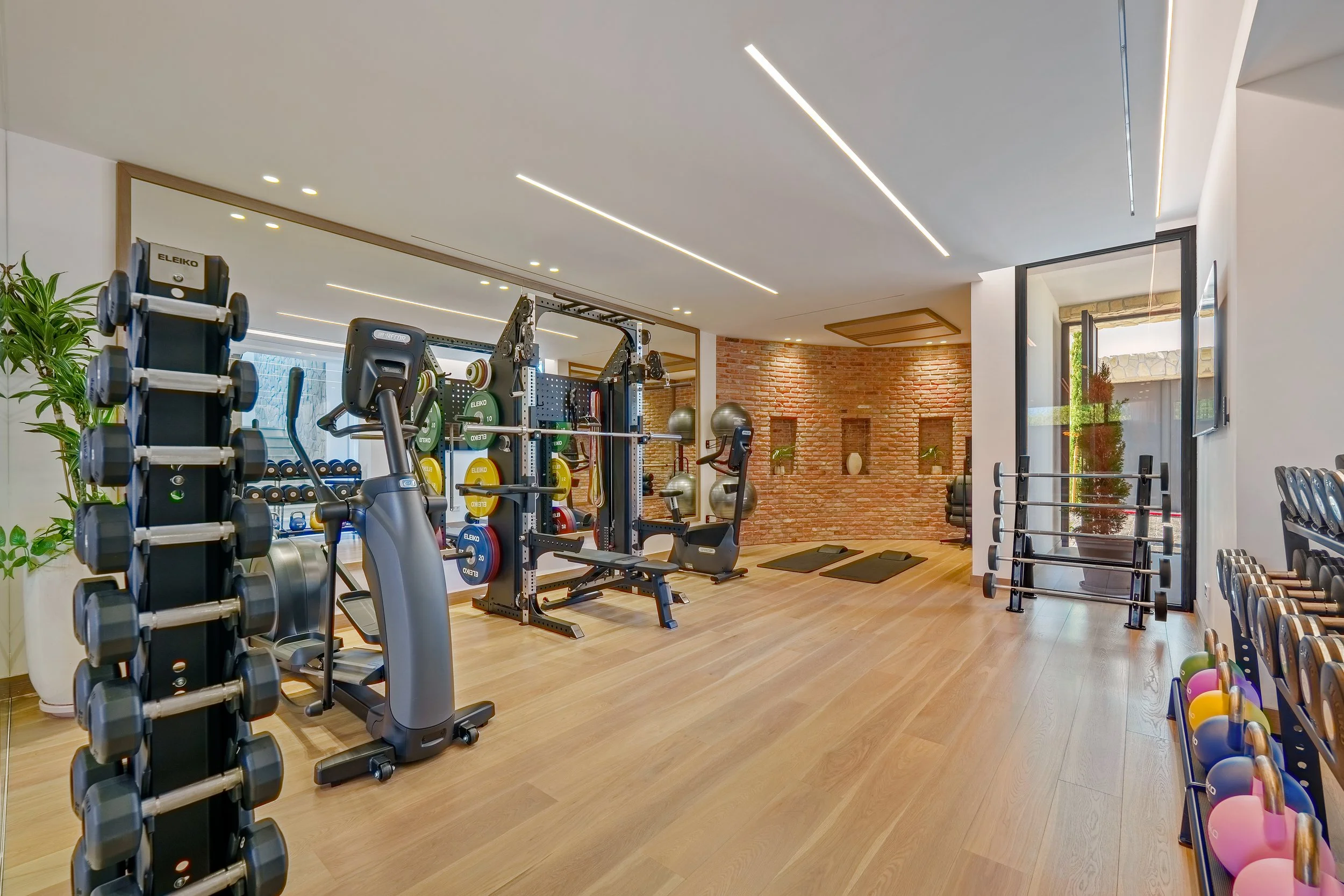 A professional-grade fitness studio with wood flooring and a comprehensive range of strength and cardio equipment.