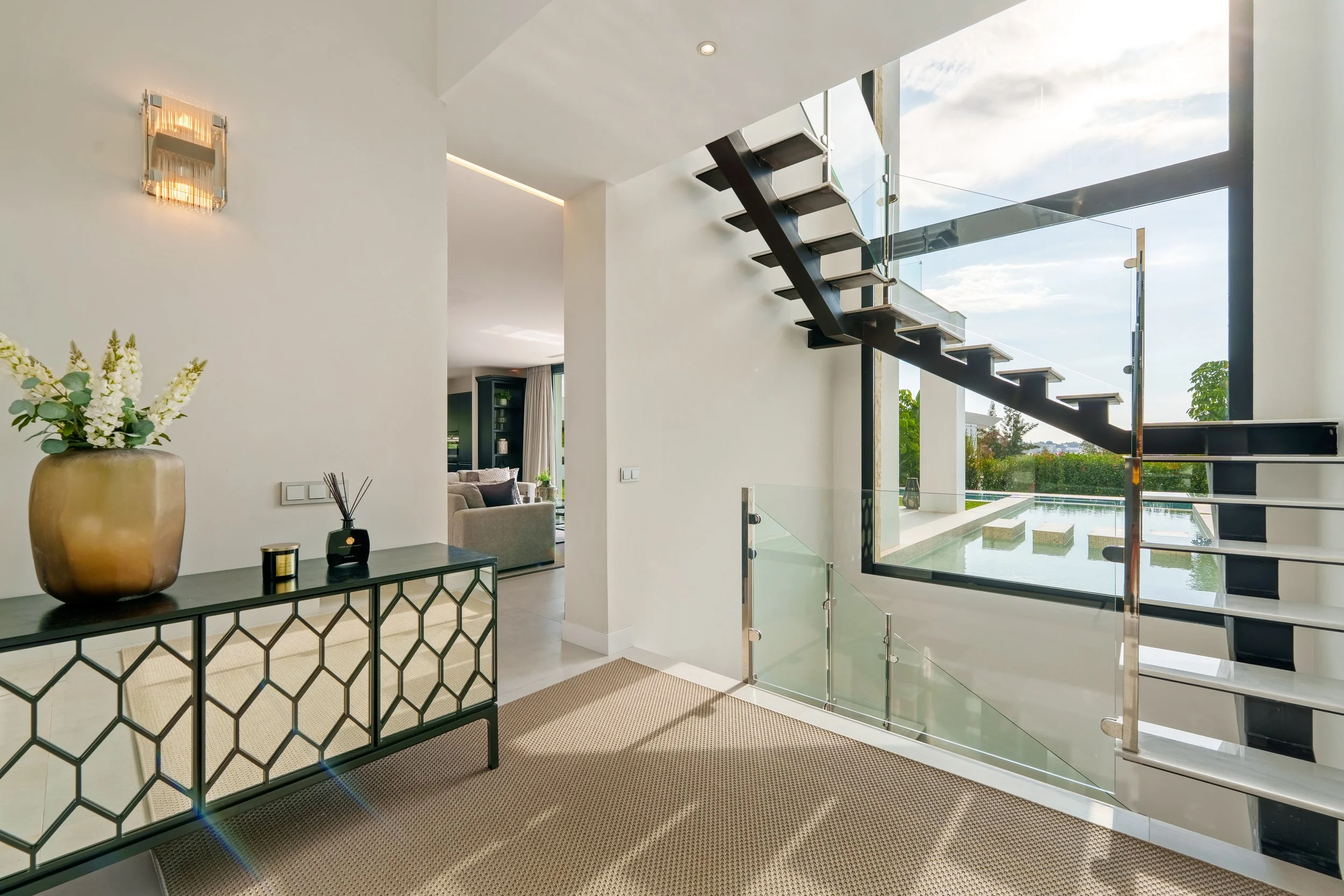 Architectural floating staircase with glass railings and a large feature window.