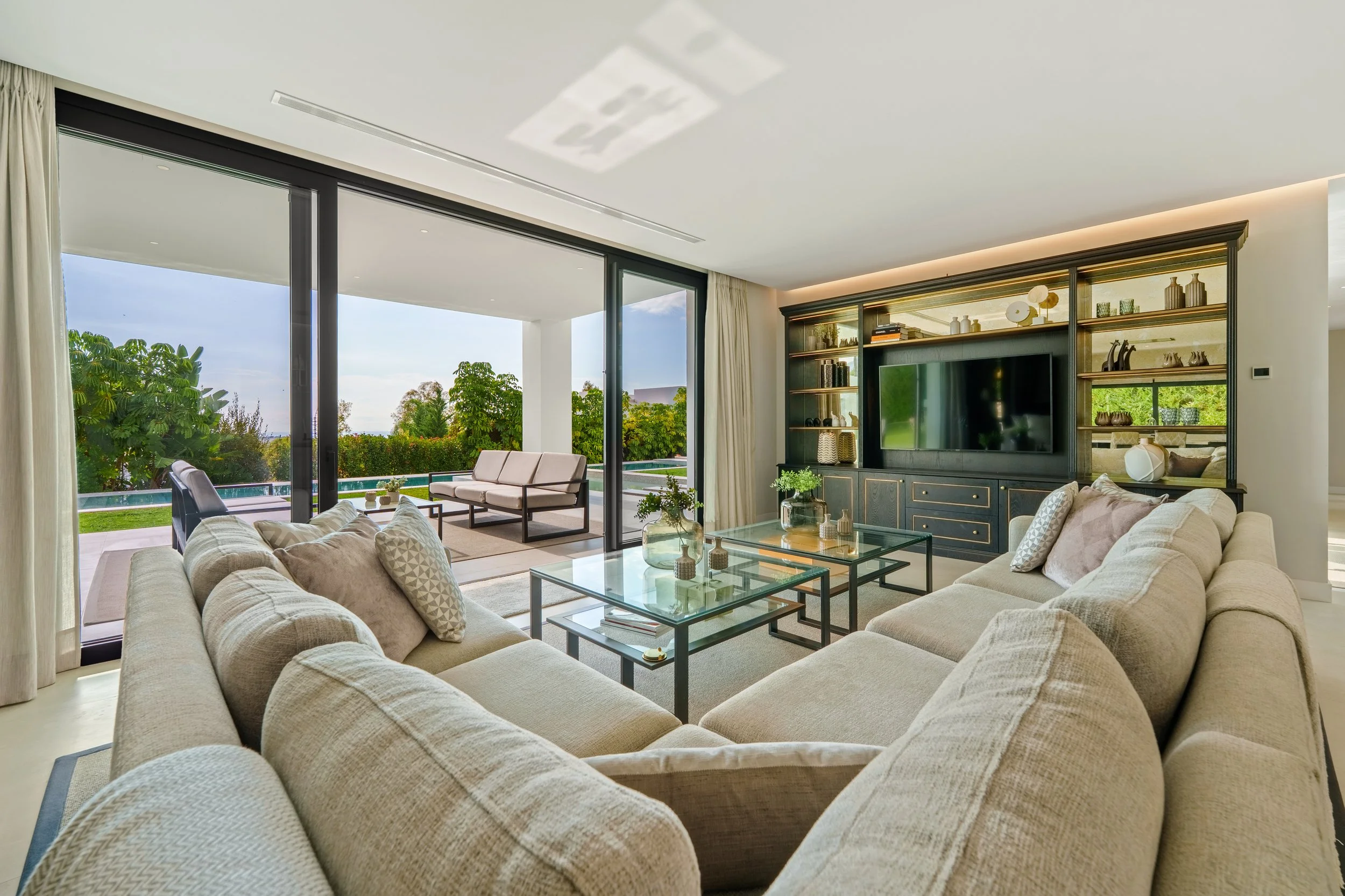 Spacious living room with neutral tones and floor-to-ceiling glass doors opening to the terrace.
