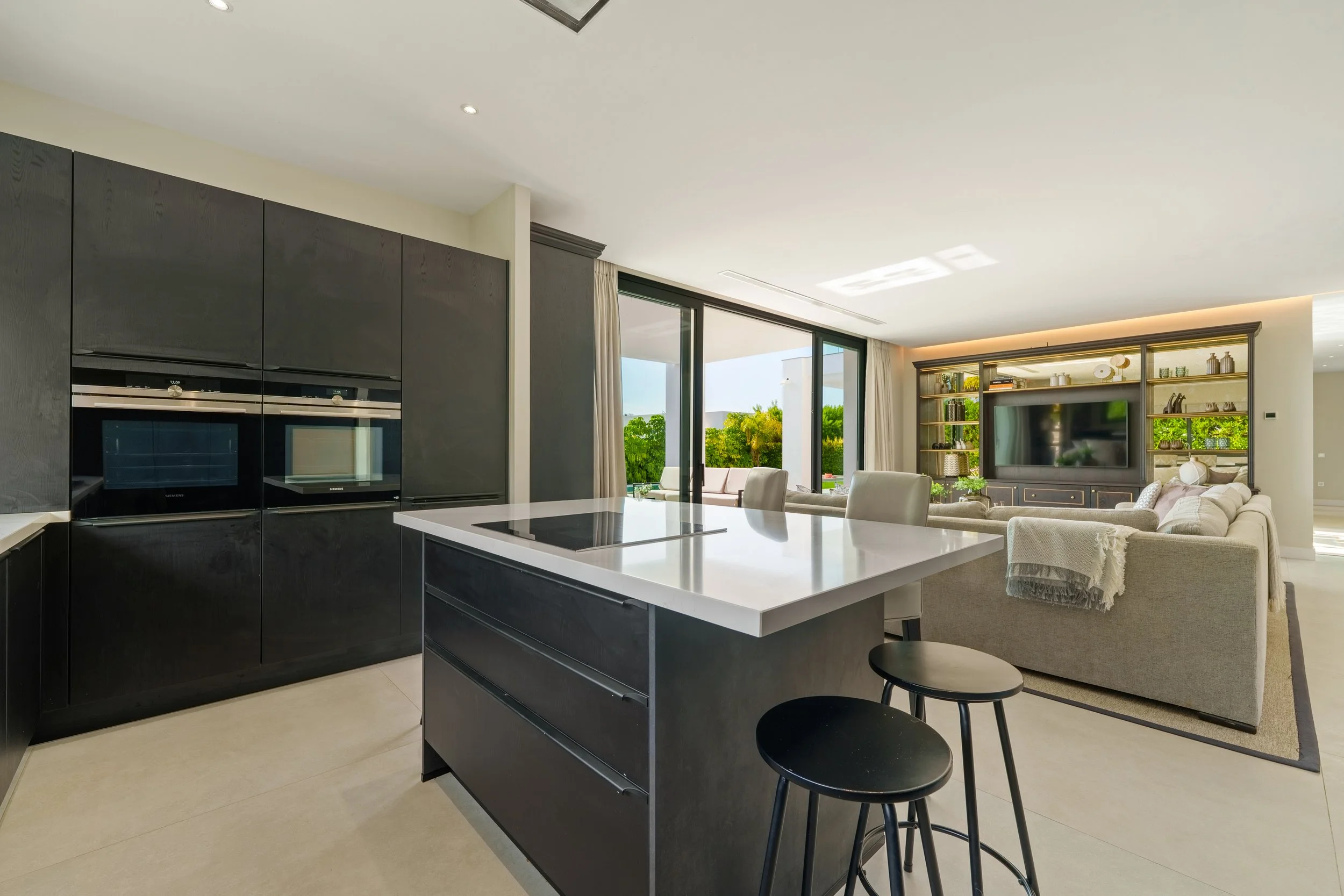 Sleek, dark minimalist kitchen featuring a large central island and high-end integrated appliances.