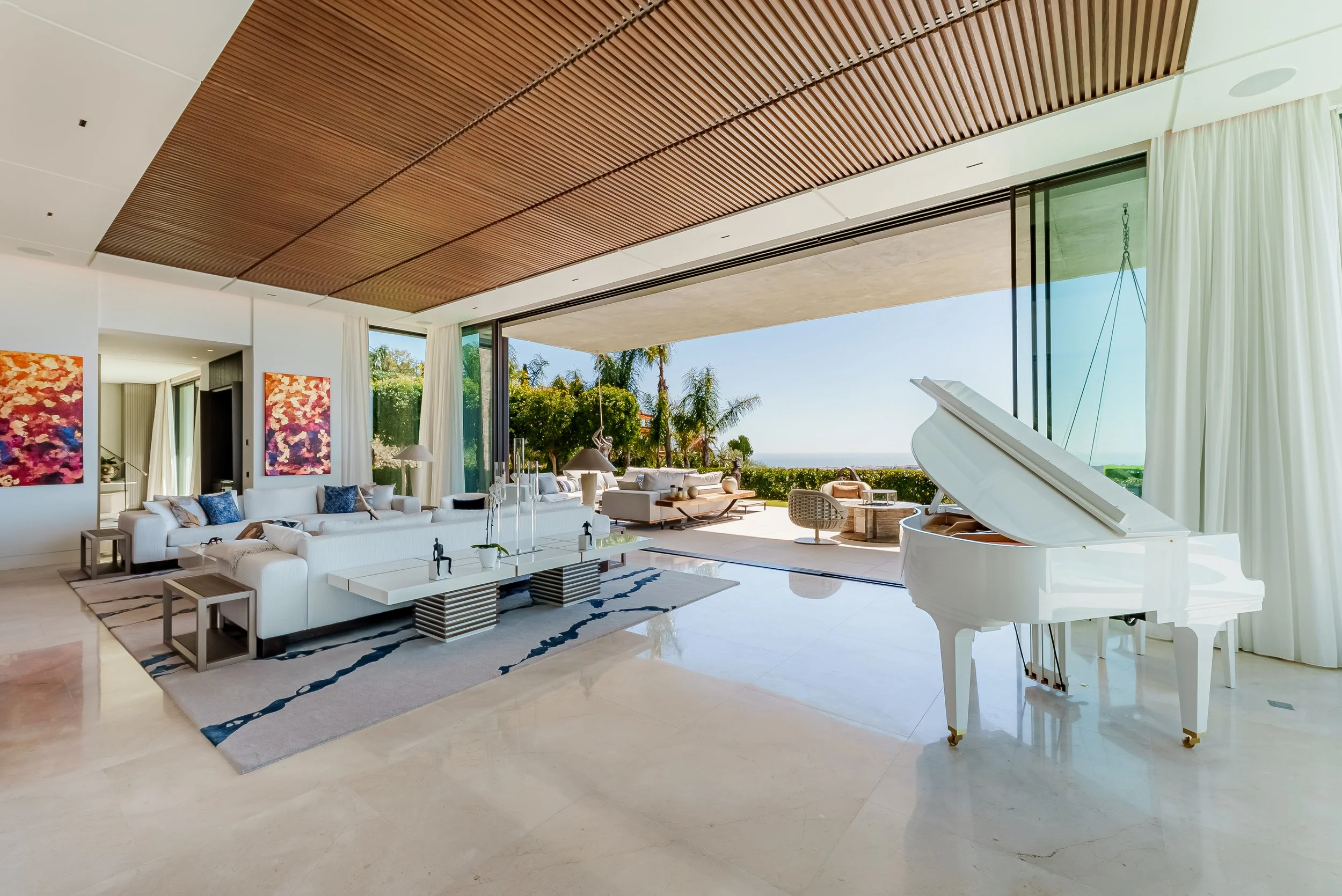 Sophisticated open-plan lounge featuring a white grand piano and bespoke ceiling details.