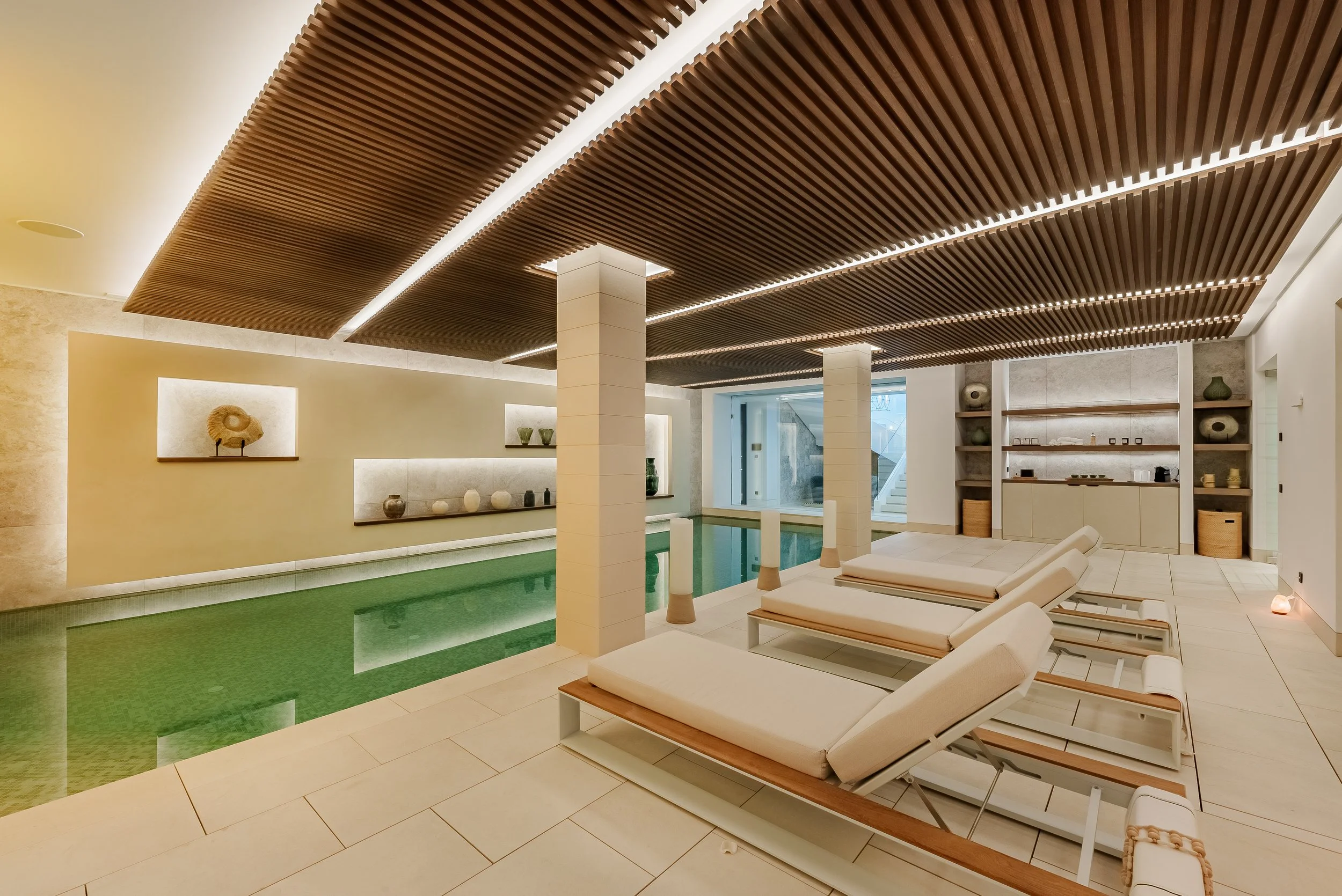 Luxury indoor wellness center featuring a heated swimming pool and wooden ceiling slats.