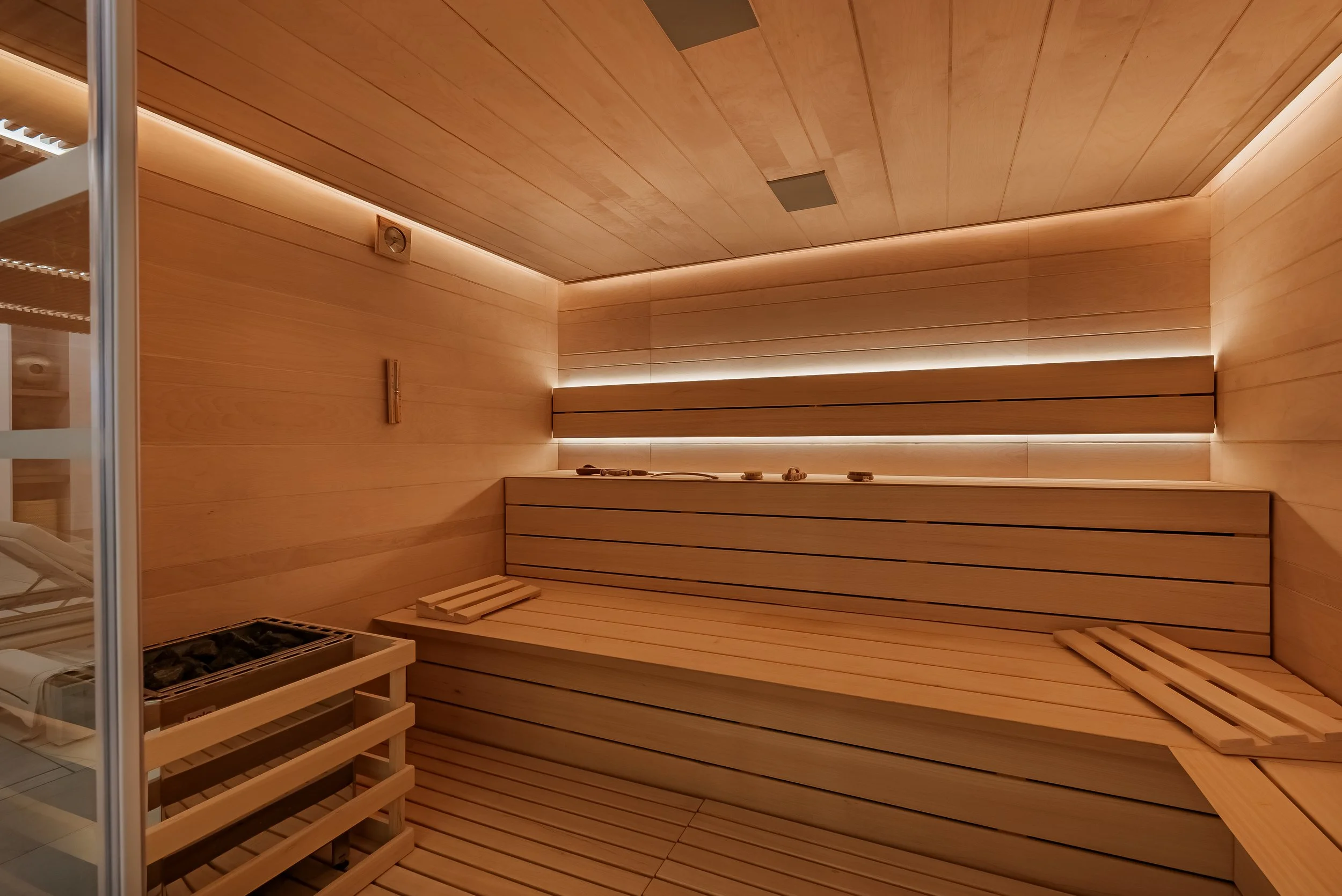 Modern wooden sauna with ambient LED strip lighting and multi-level seating.