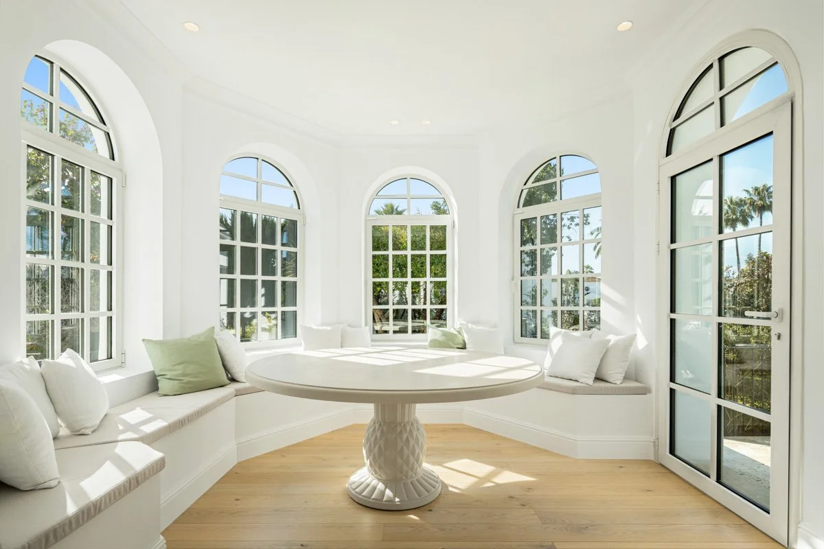 Unique curved breakfast nook with arched windows and garden views in a luxury Mediterranean home.