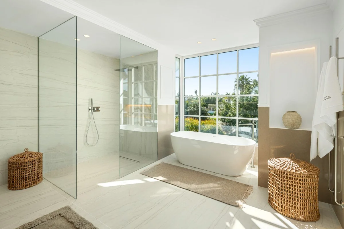 Modern en-suite bathroom with a freestanding soaking tub and large glass-enclosed rain shower.