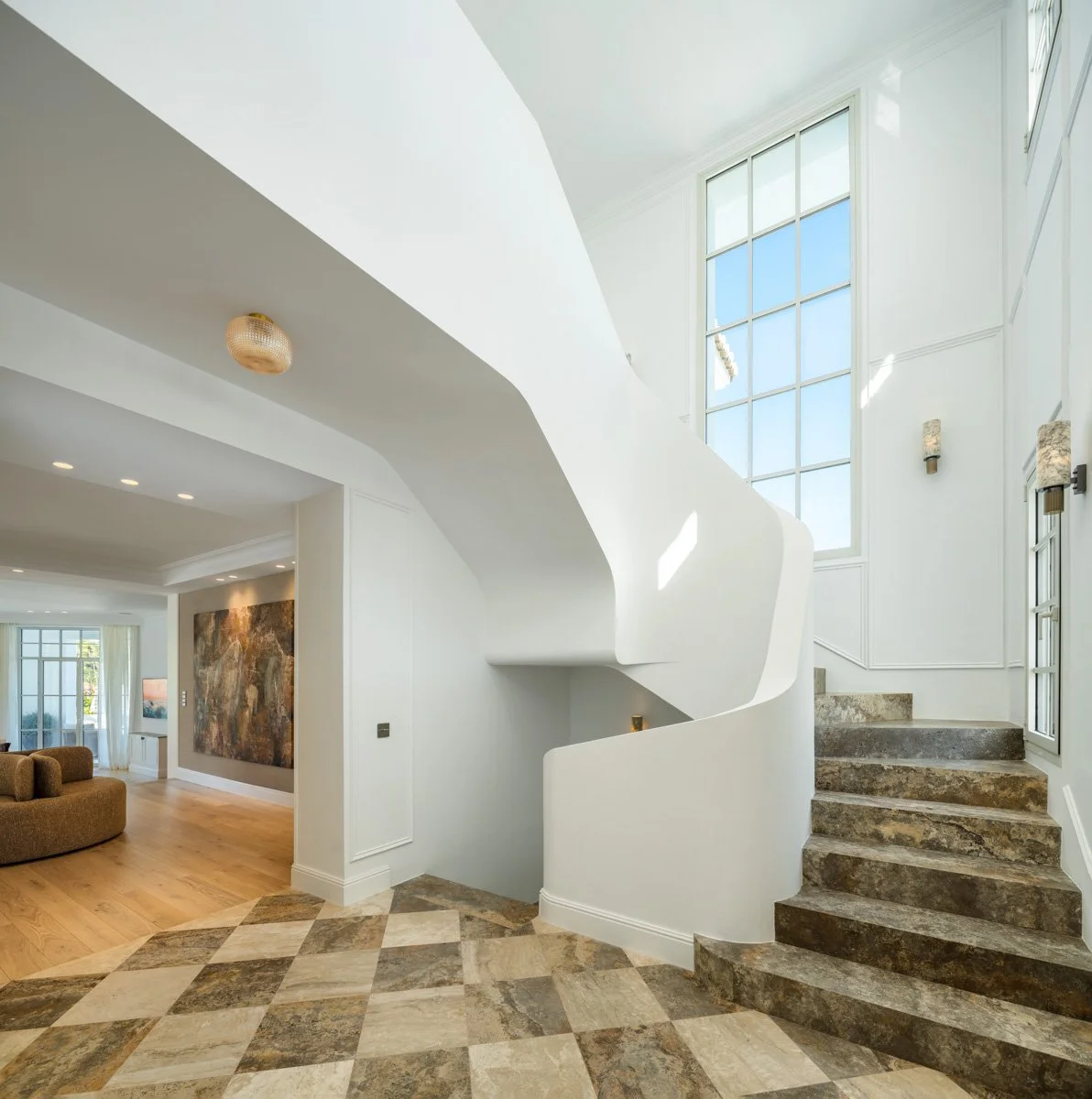Elegant white spiral staircase with natural light from large windows in a luxury Marbella villa.