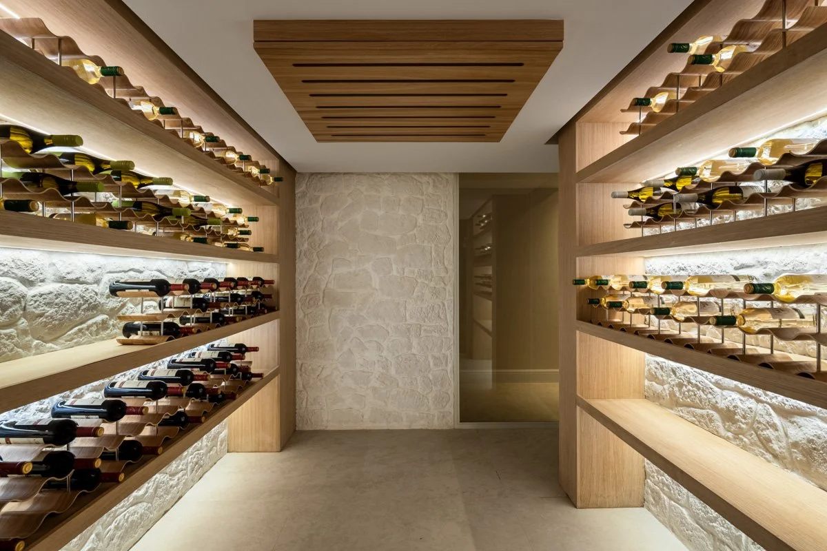 Temperature-controlled custom wine bodega with integrated lighting and stone wall accents