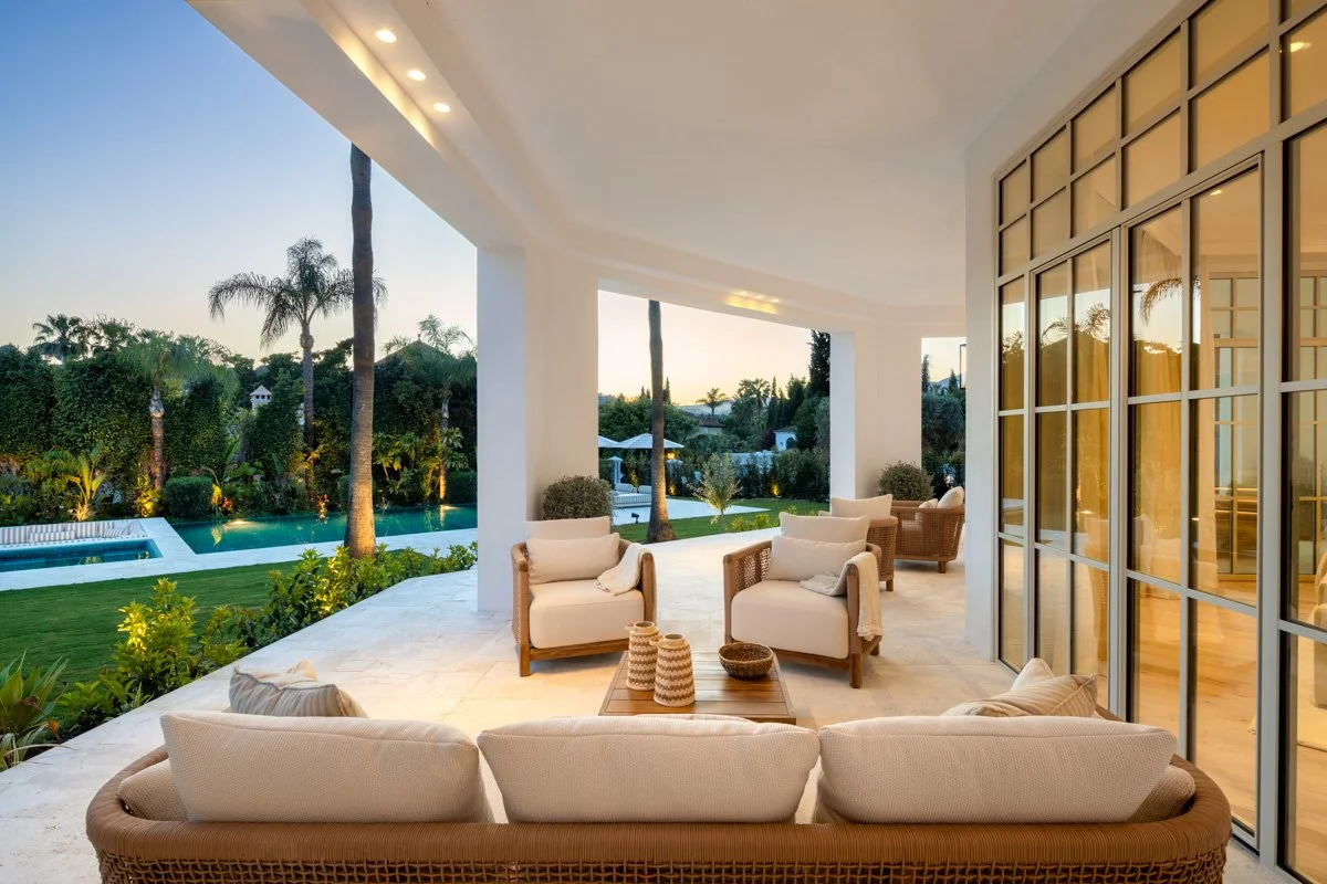 Evening view of the illuminated covered terrace and gardens in Nueva Andalucia.