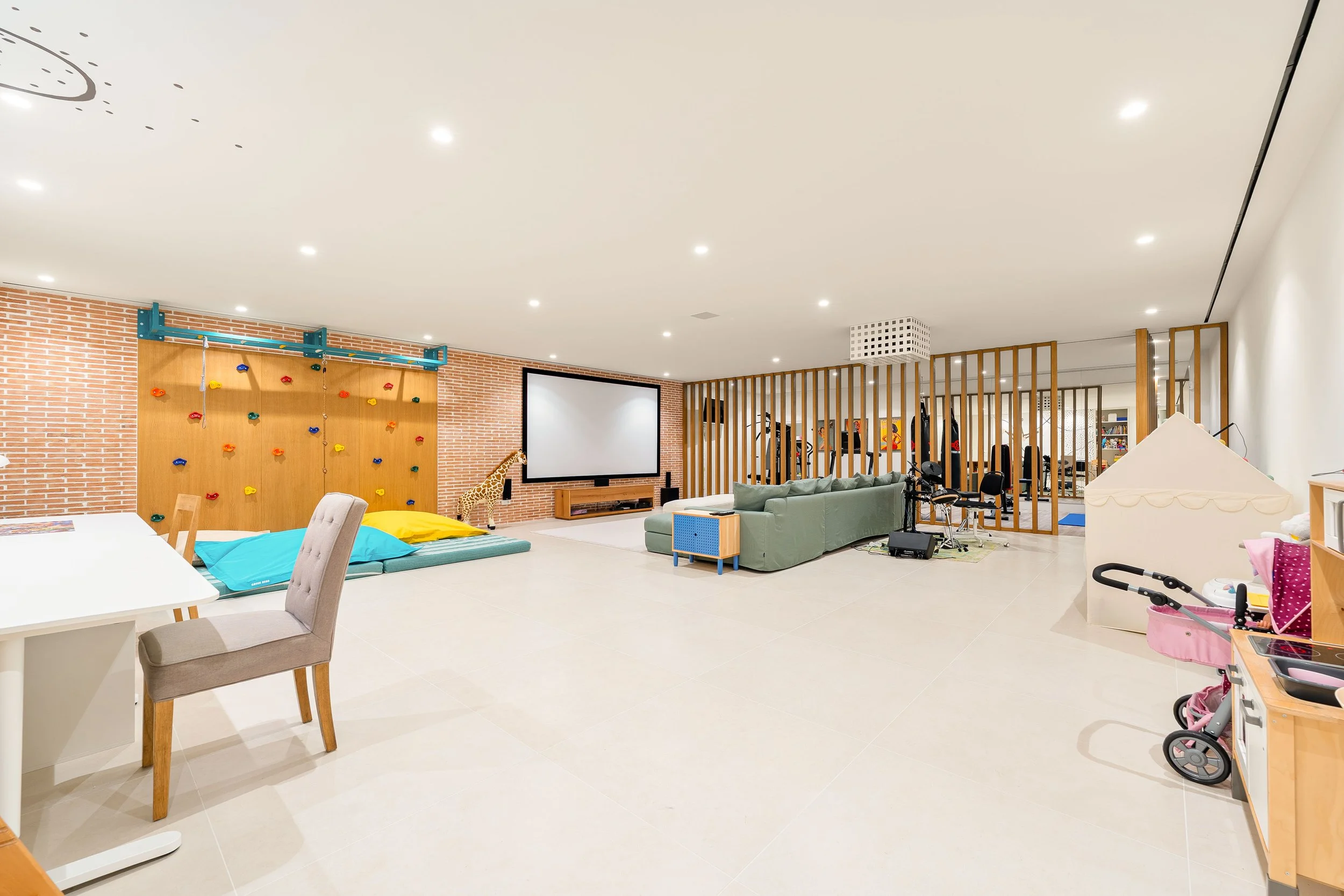 Large lower-level entertainment zone with a home cinema screen, comfortable lounge area, and flexible leisure space.